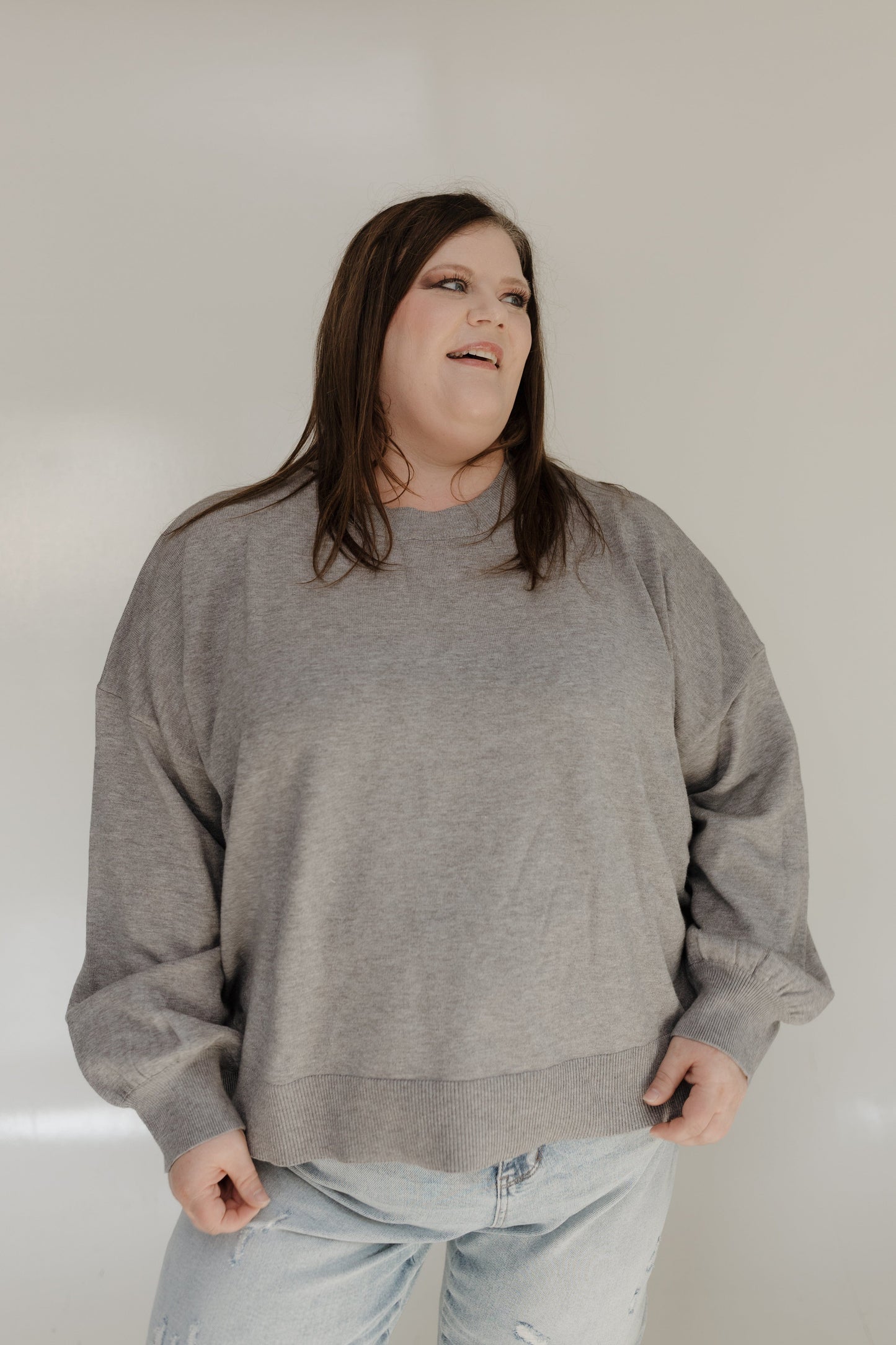 Person wearing a gray sweatshirt against a plain background