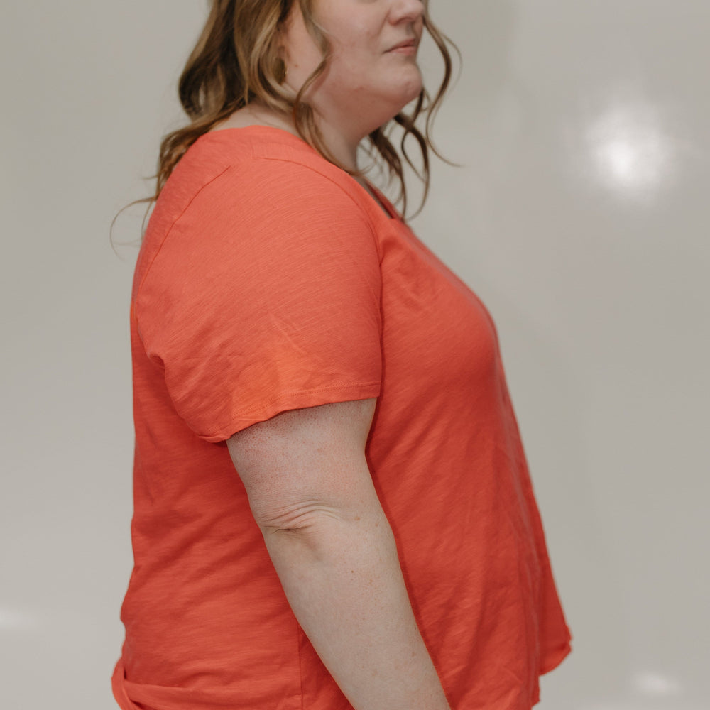 Woman wearing an orange shirt against a plain background