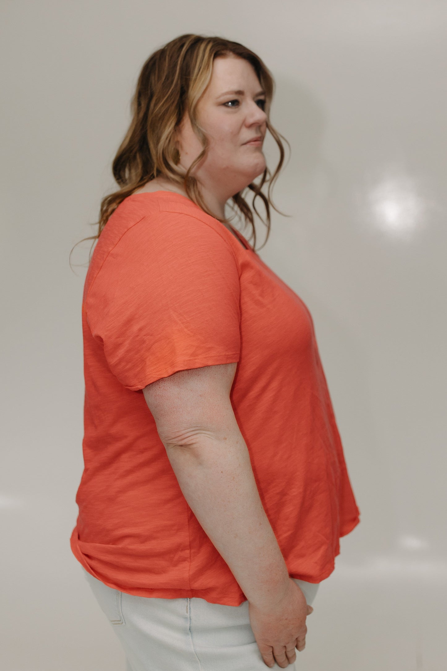 Woman wearing an orange shirt against a plain background