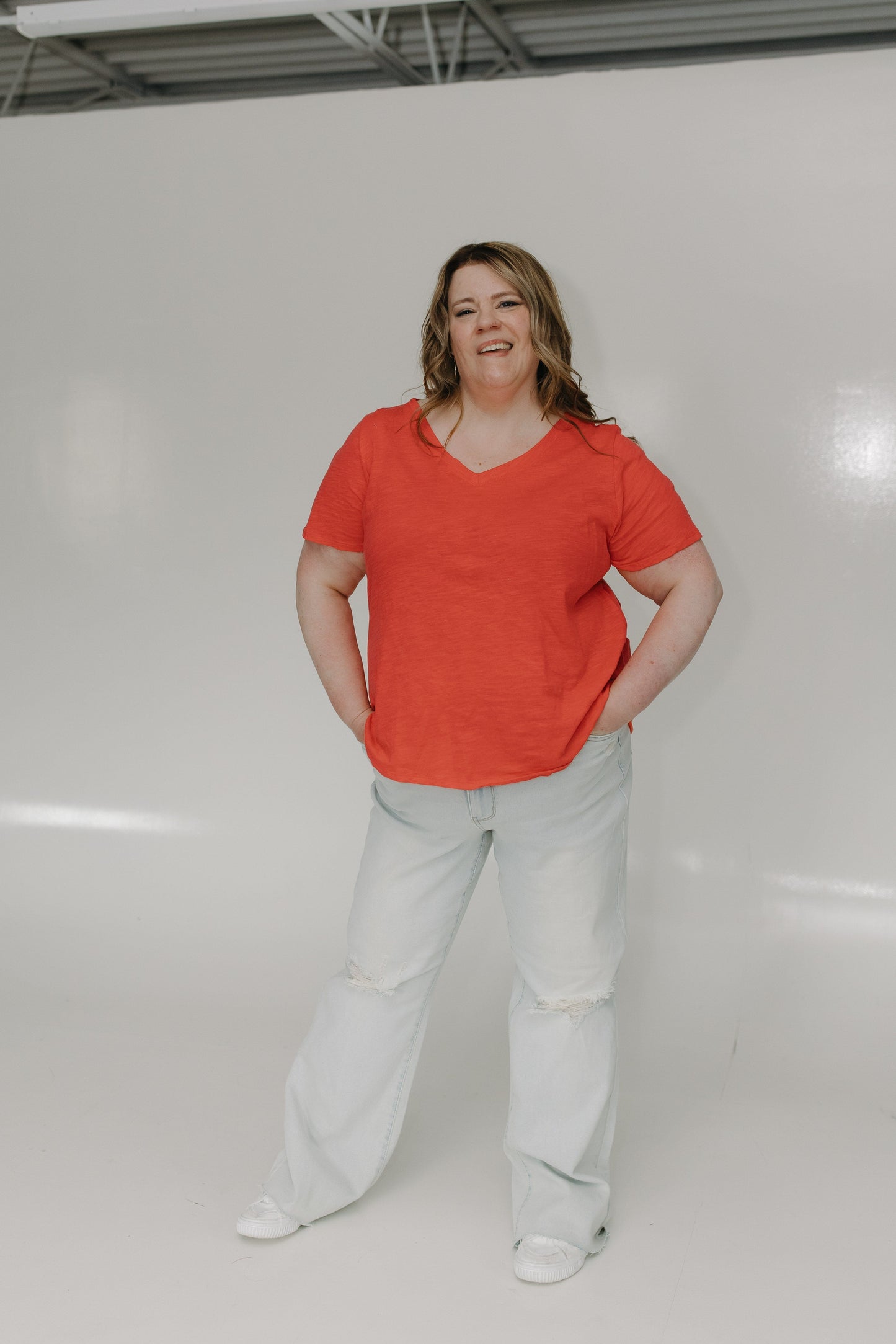 Person wearing a red shirt and light gray pants against a white background