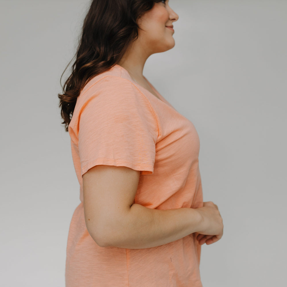 Woman wearing a peach-colored shirt against a plain background