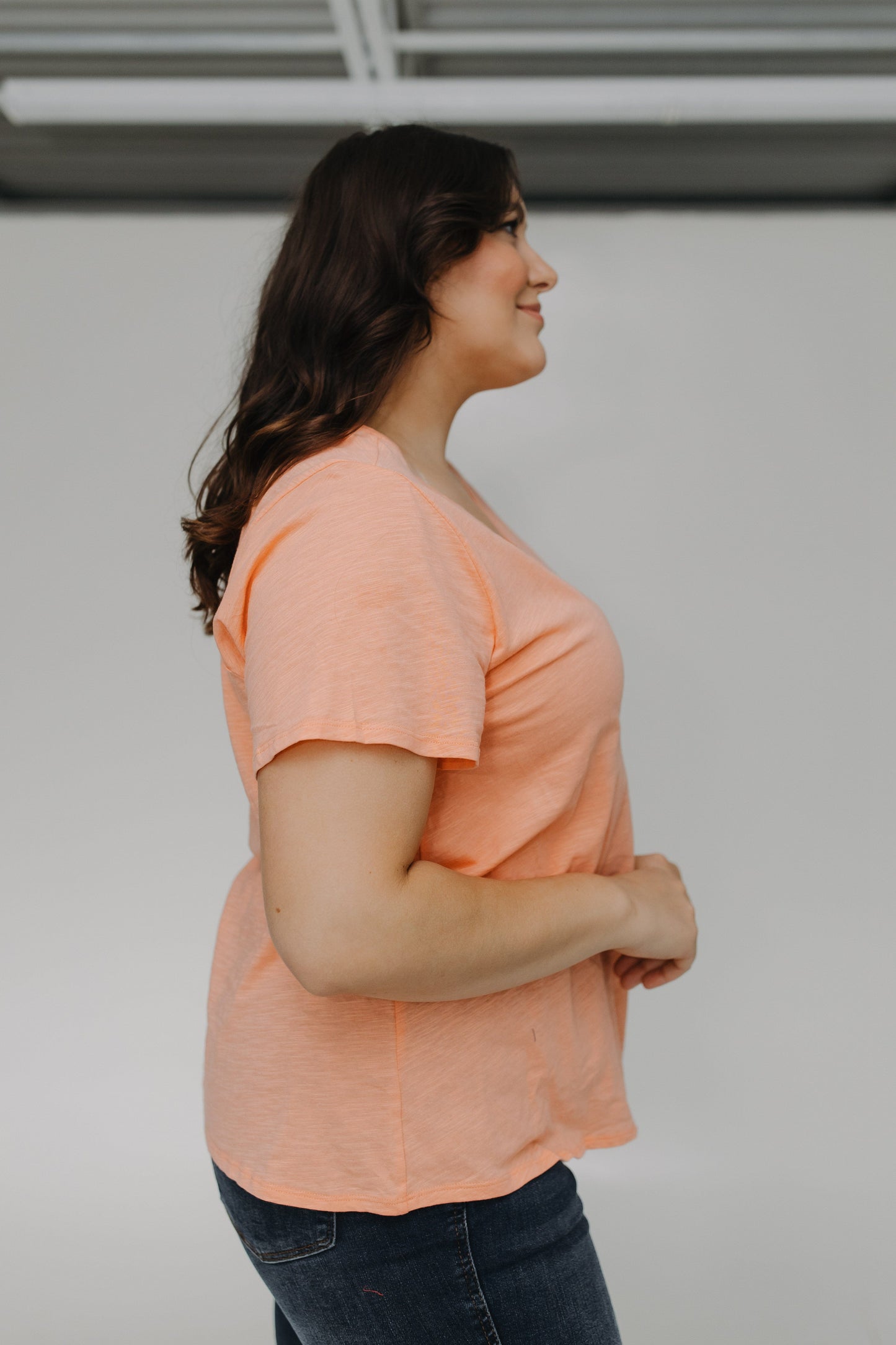 Woman wearing a peach-colored shirt against a plain background