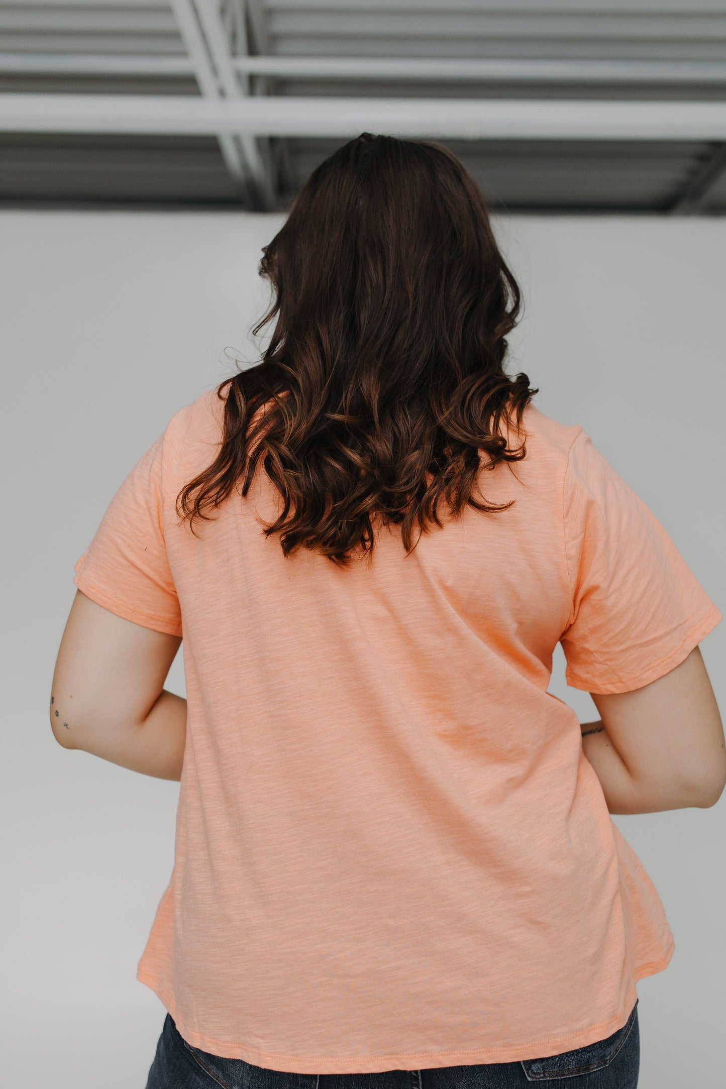 Person wearing a peach-colored t-shirt with a plain background