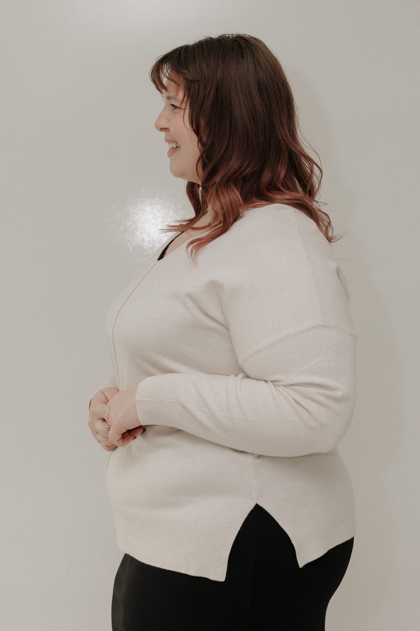 Woman wearing a light-colored sweater against a plain background