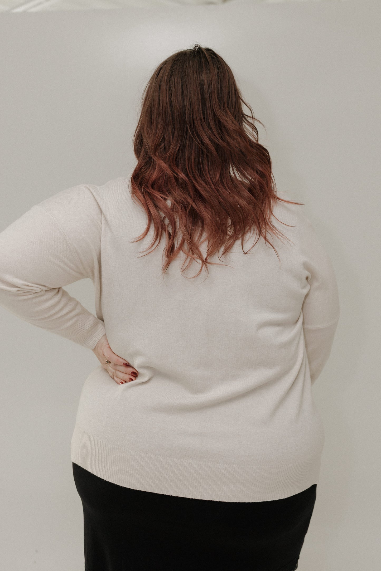 Person wearing a beige sweater against a plain background