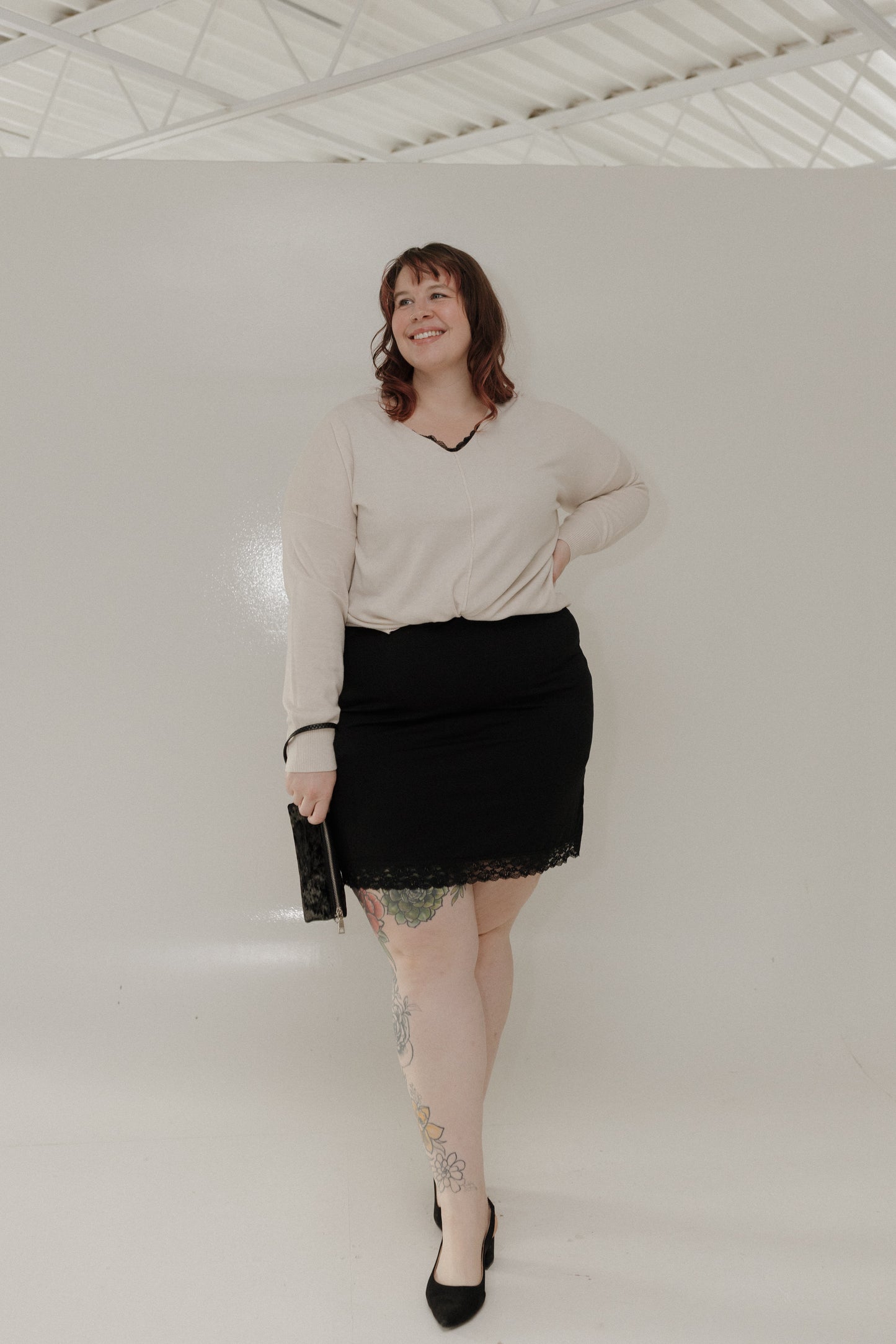 Woman wearing a beige sweater and black skirt against a white background