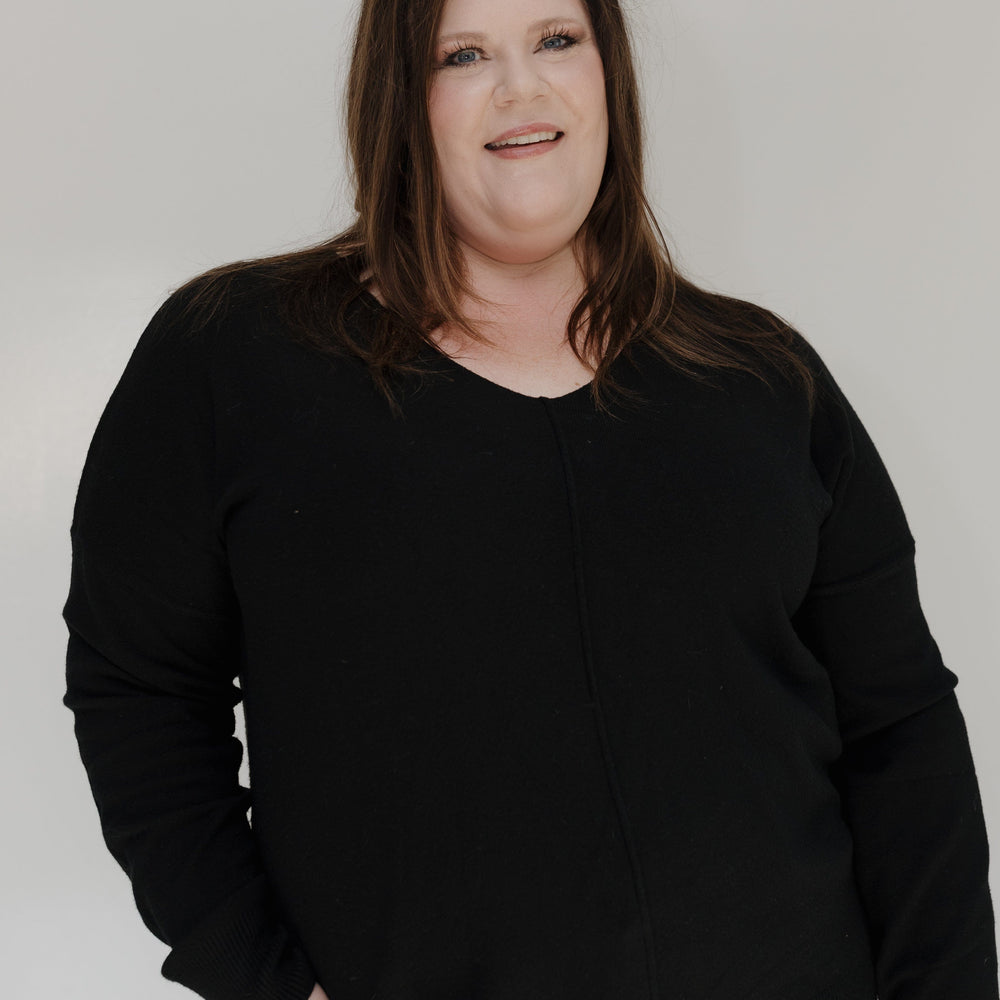 Person wearing a black sweater against a white background