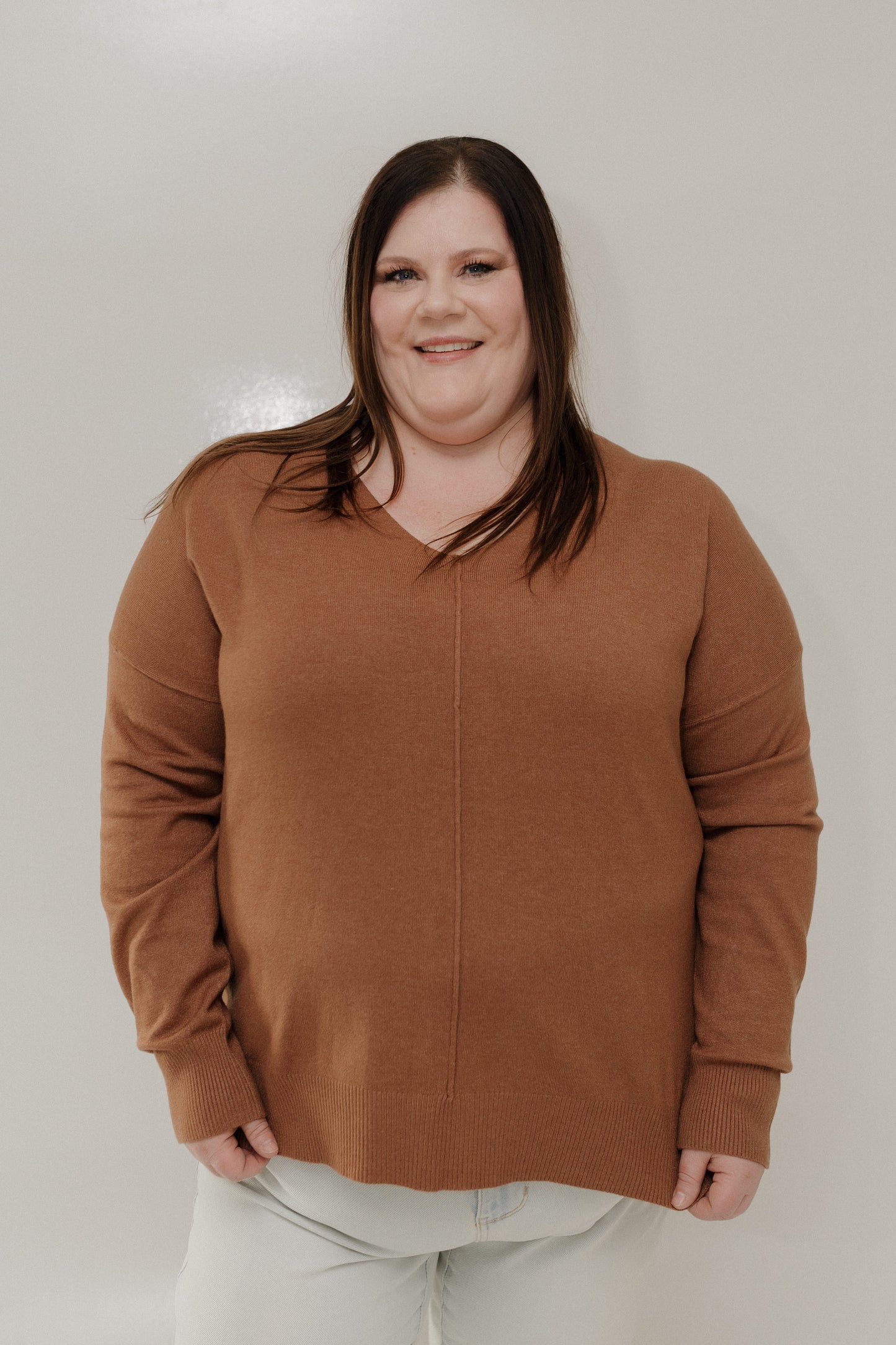 Woman wearing a brown sweater against a plain background