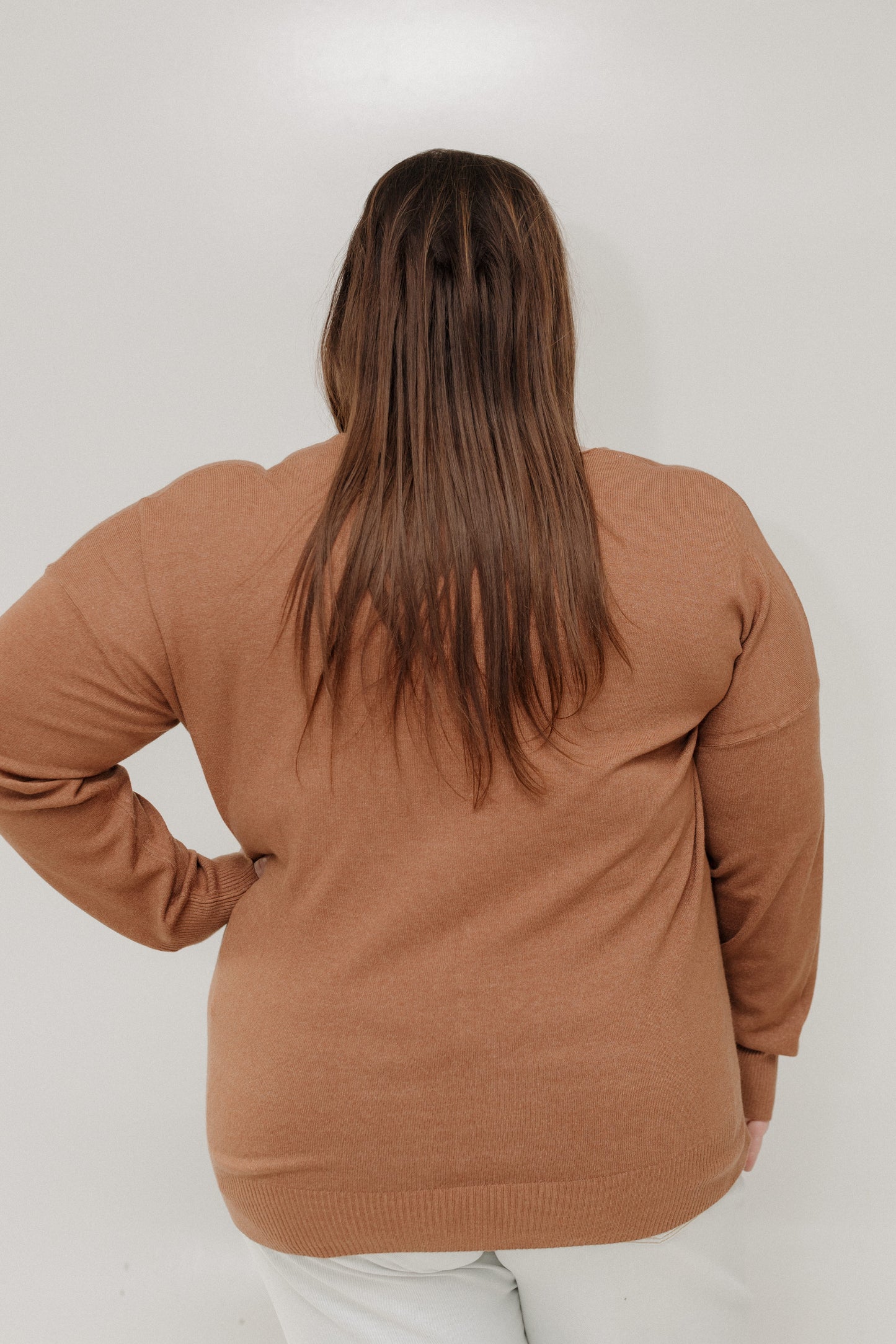 Person wearing a brown sweater on a white background