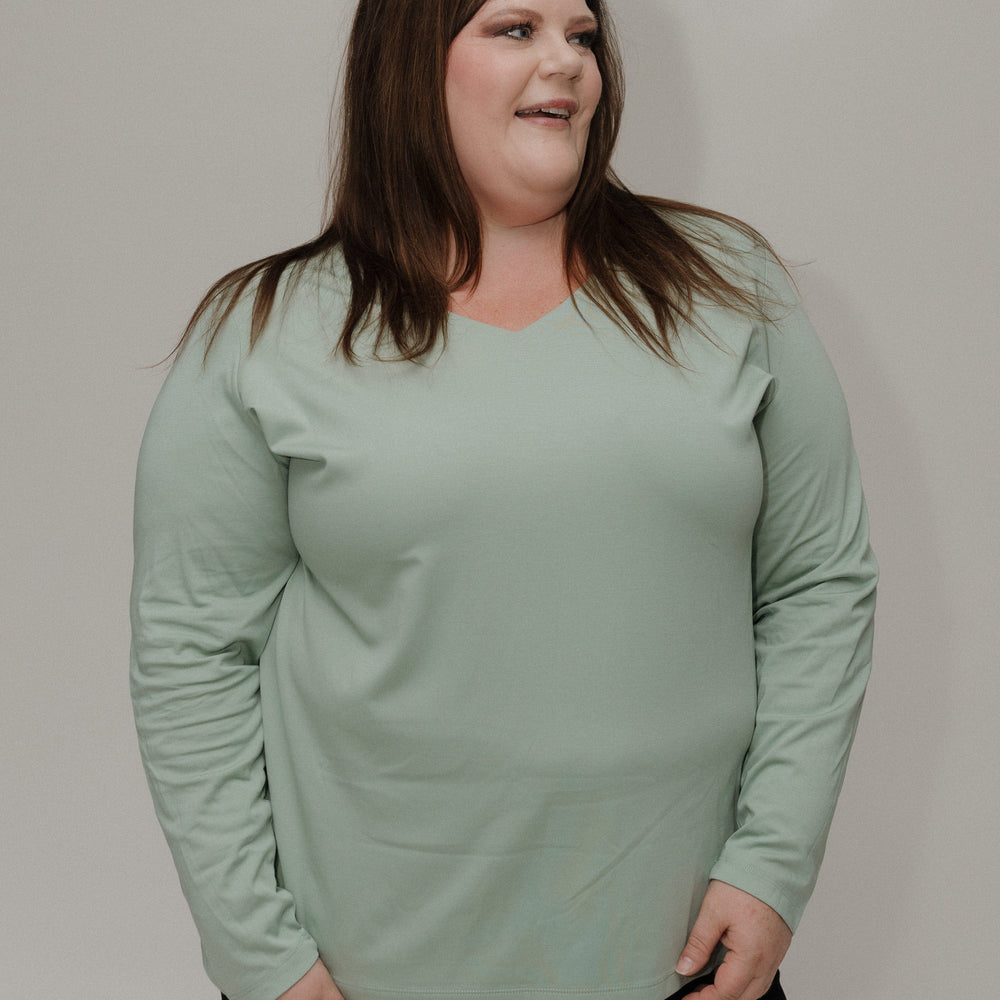 Person wearing a light green long-sleeve shirt against a plain background