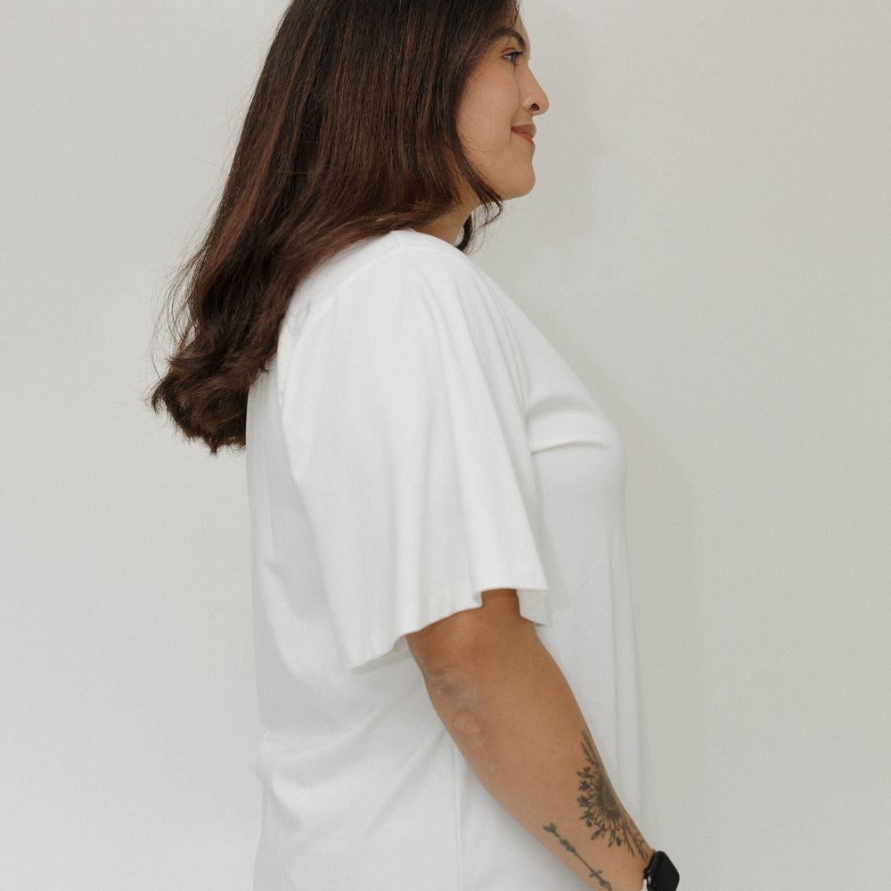Person wearing a white t-shirt against a plain background