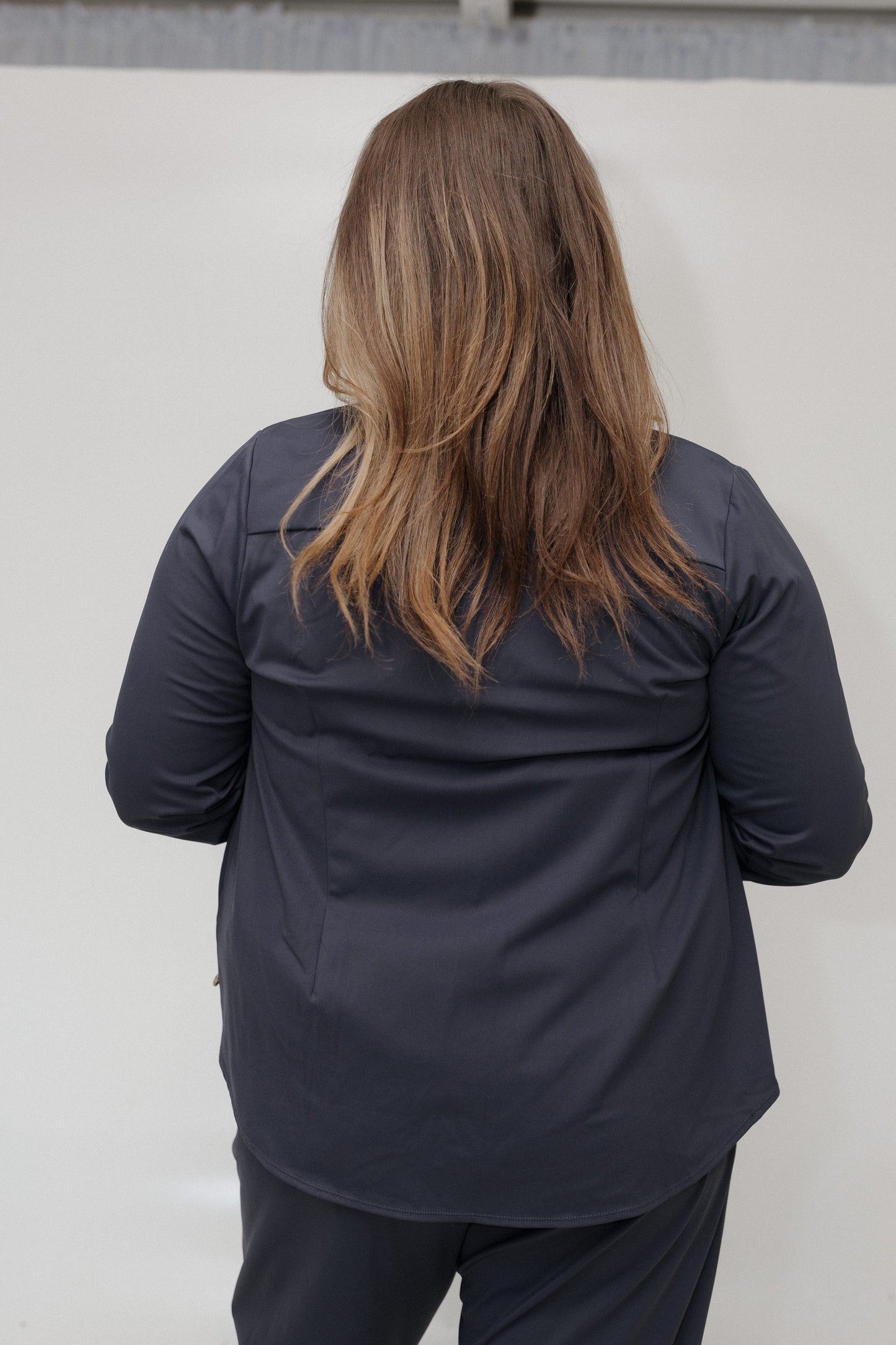 Person wearing a dark jacket and pants against a light background