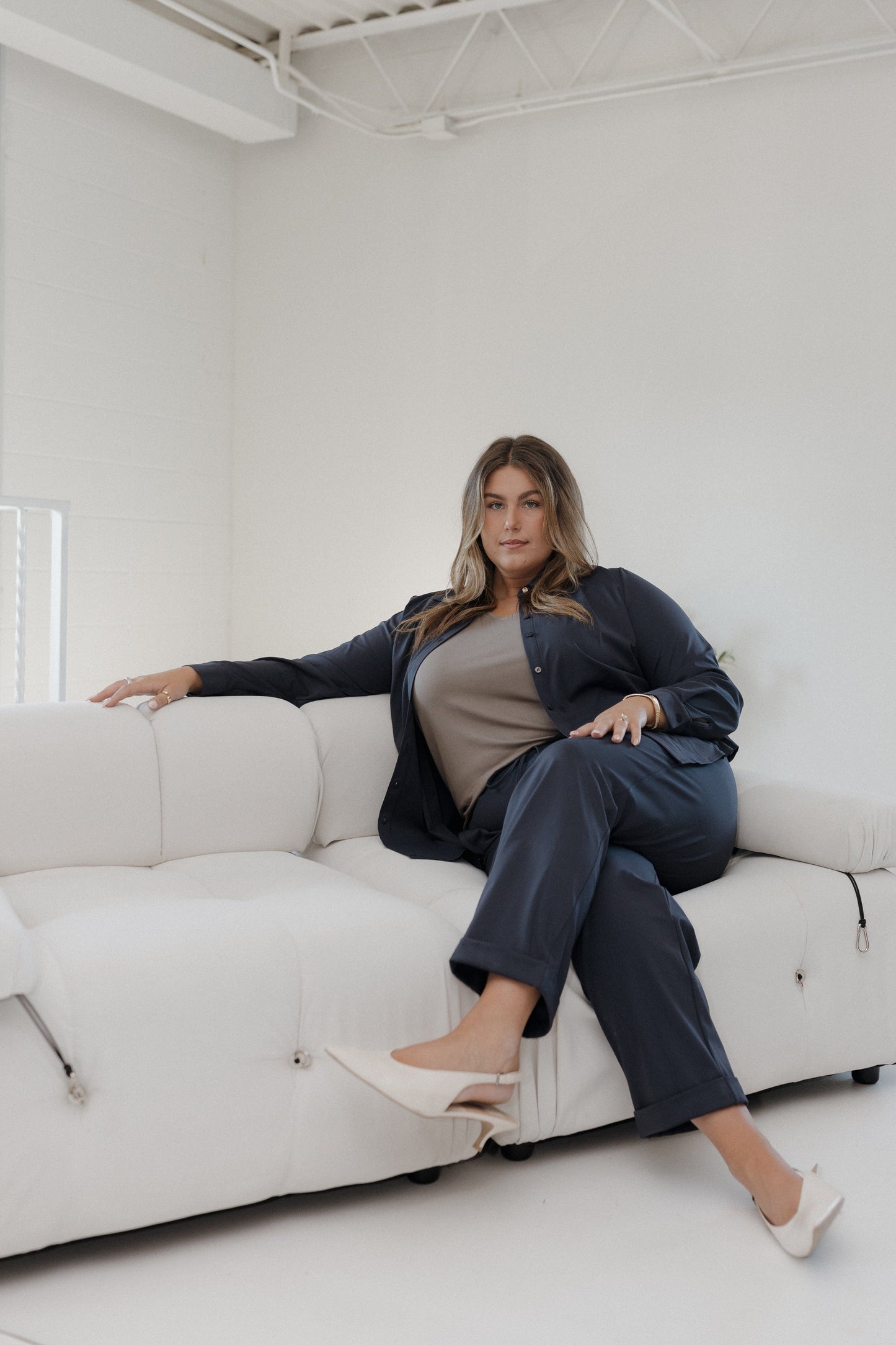 Woman sitting on a white couch in a minimalistic room