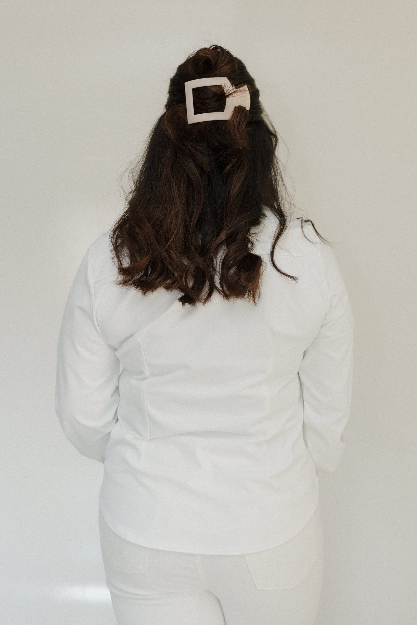 Person wearing a white outfit with a large bow headband against a plain background