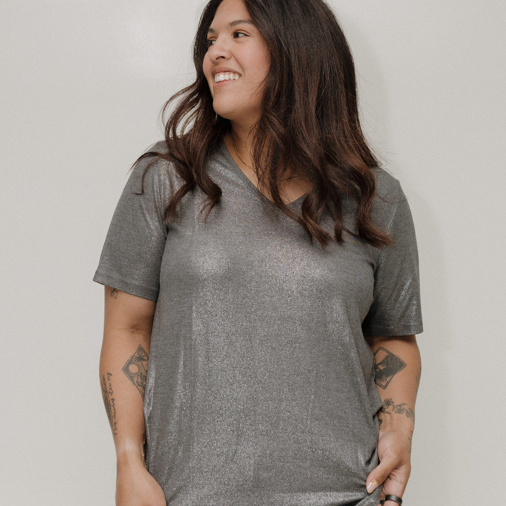 Woman wearing a gray t-shirt and leopard print pants against a plain background