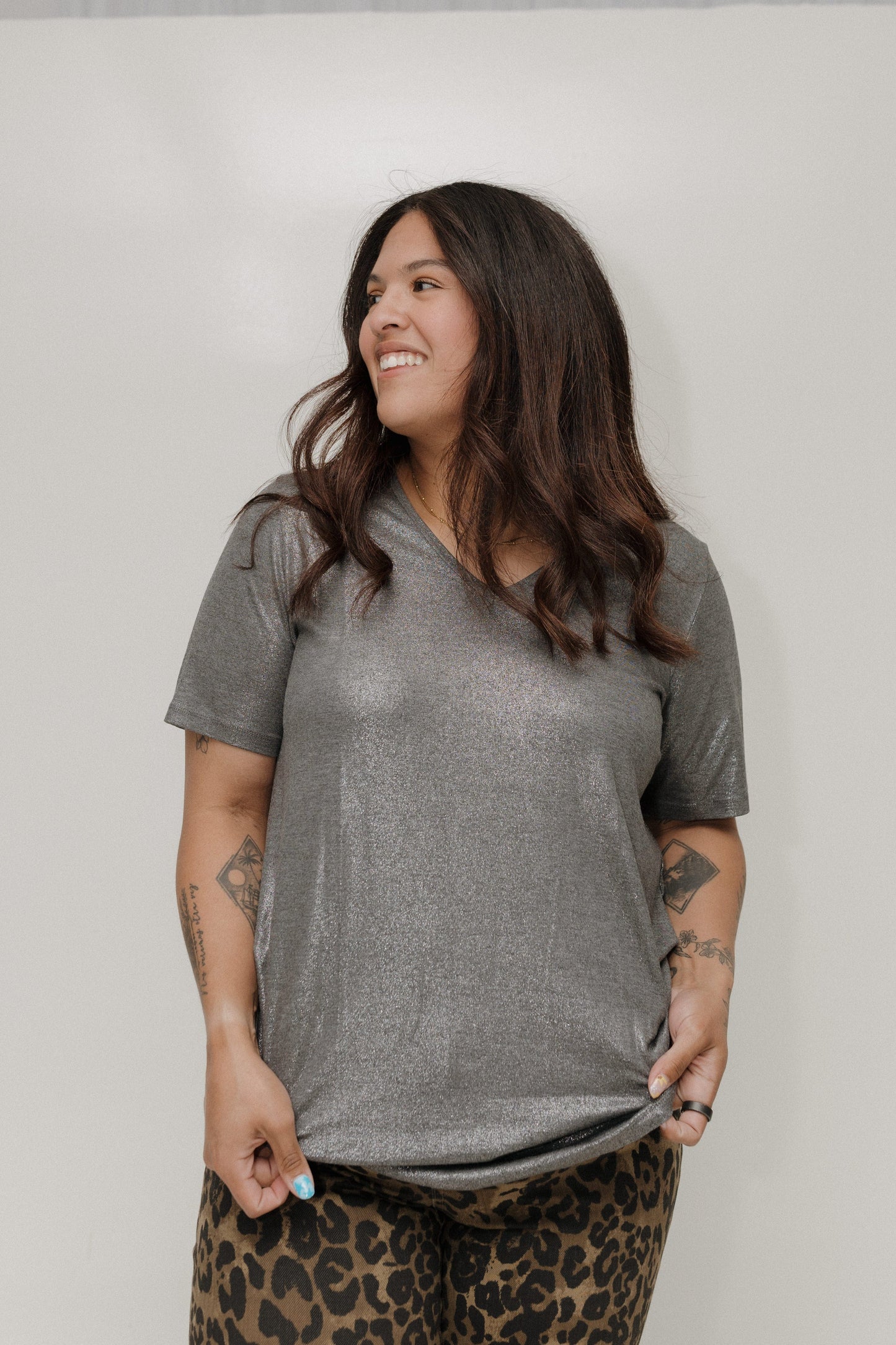 Woman wearing a gray t-shirt and leopard print pants against a plain background