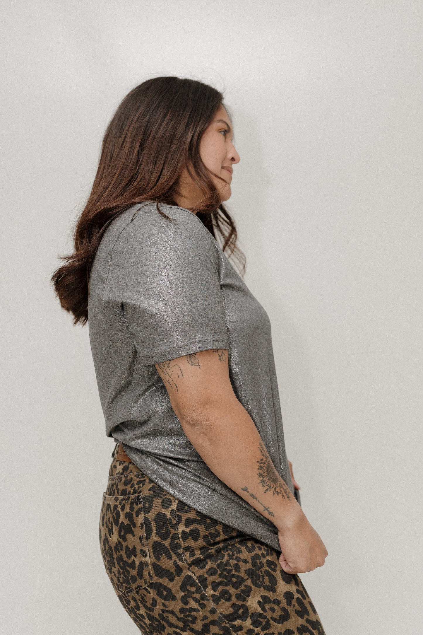 Woman wearing a gray t-shirt and leopard print skirt against a plain background