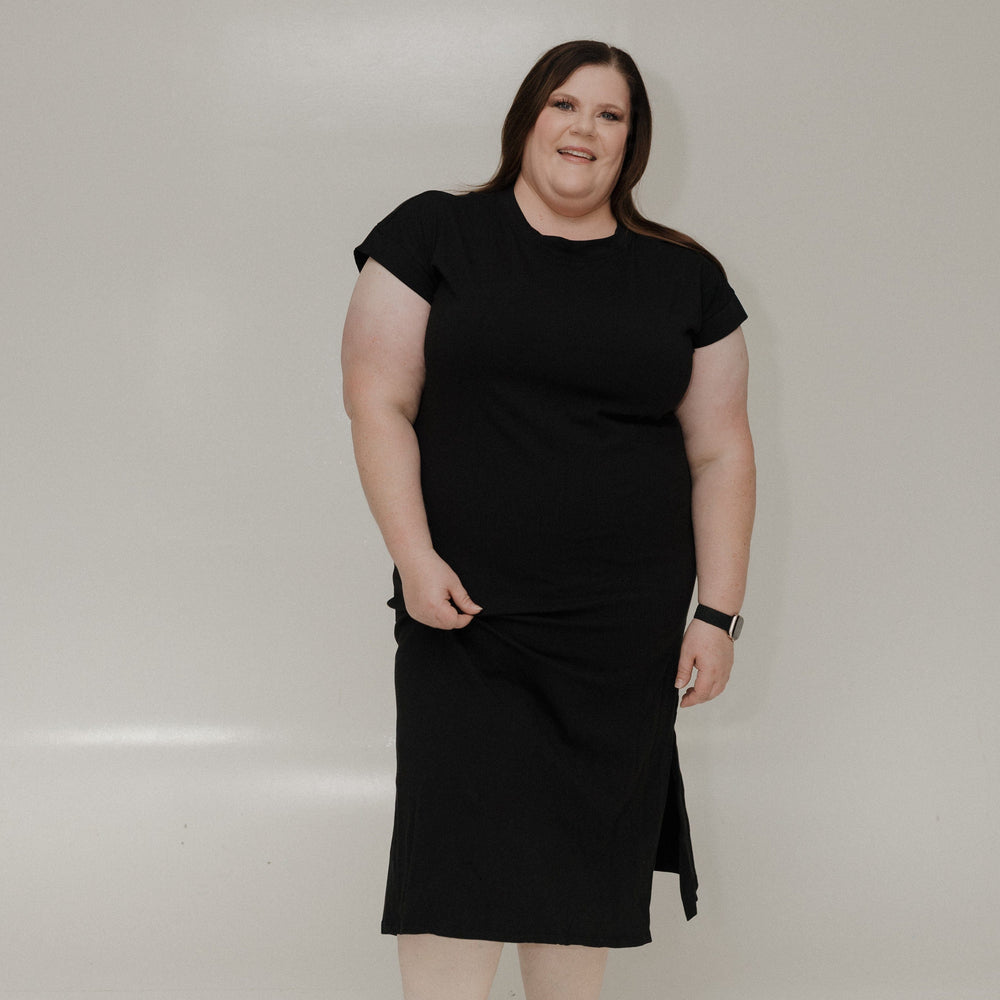 Woman wearing a black dress standing against a white background