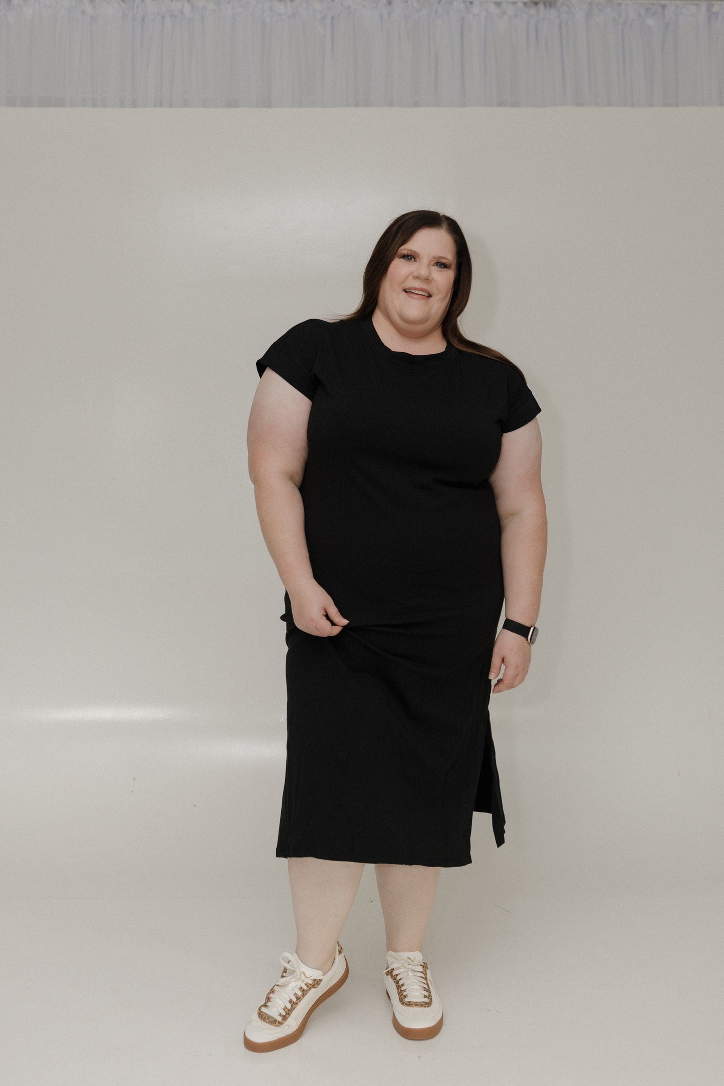 Woman wearing a black dress standing against a white background