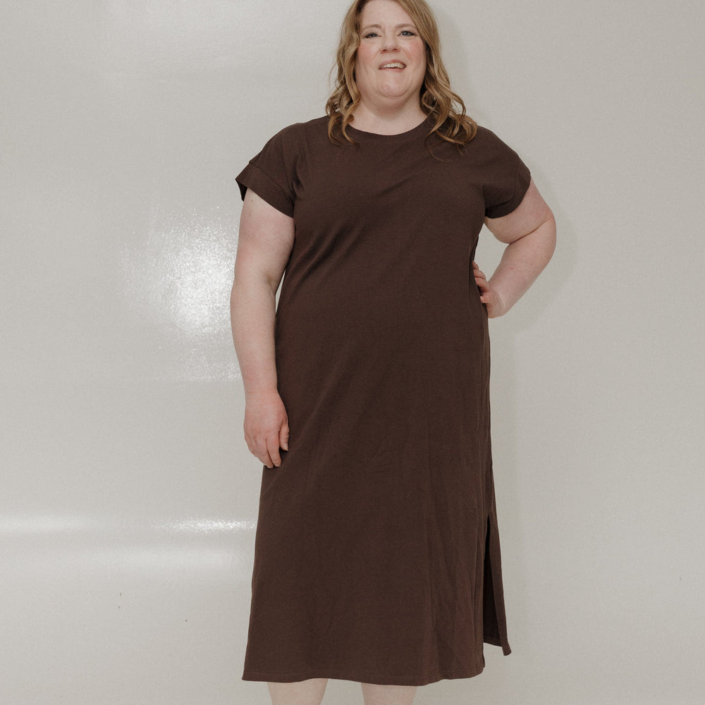 Woman wearing a brown dress standing against a white background