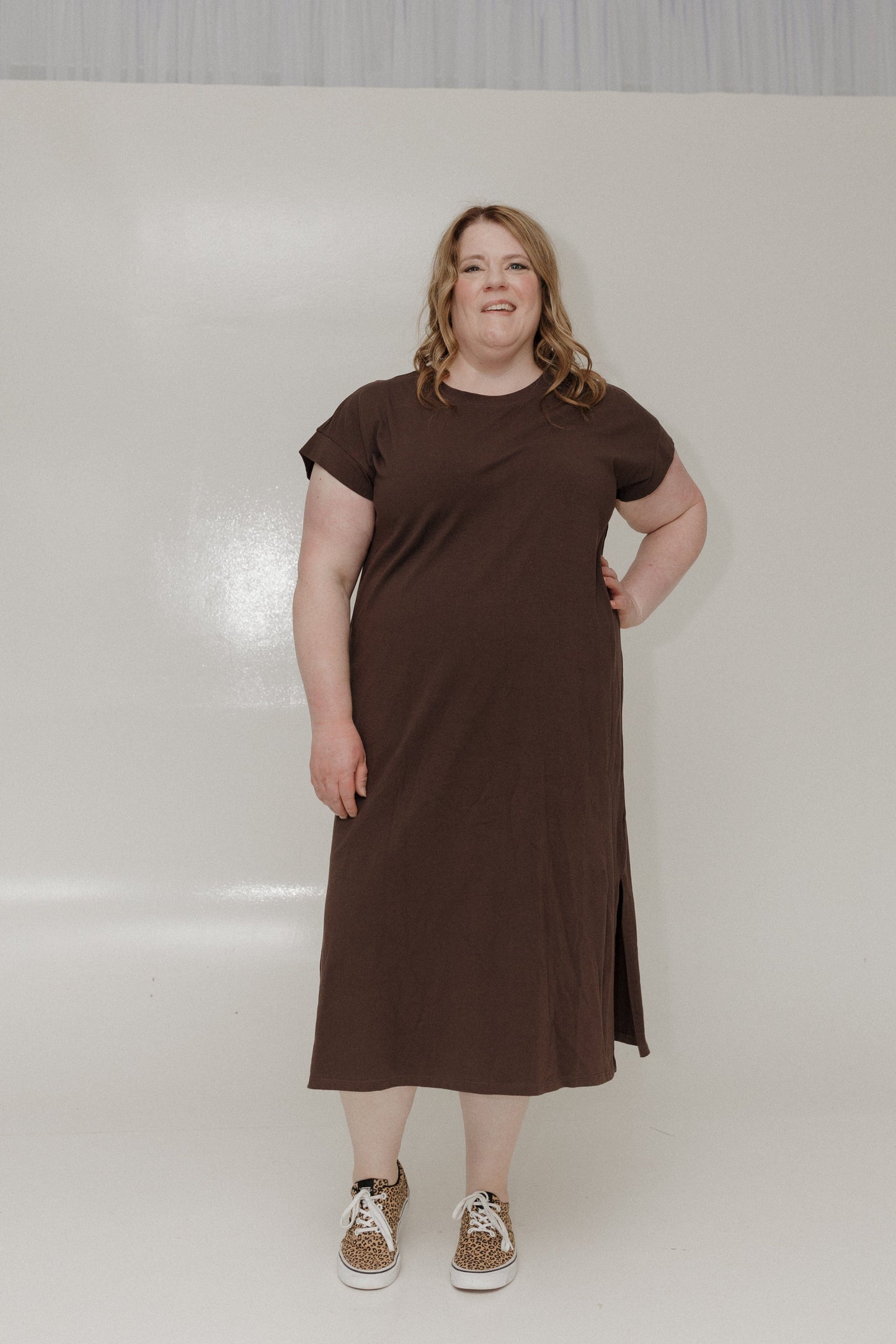 Woman wearing a brown dress standing against a white background