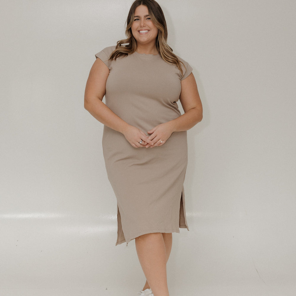 Woman wearing a beige dress standing against a plain background