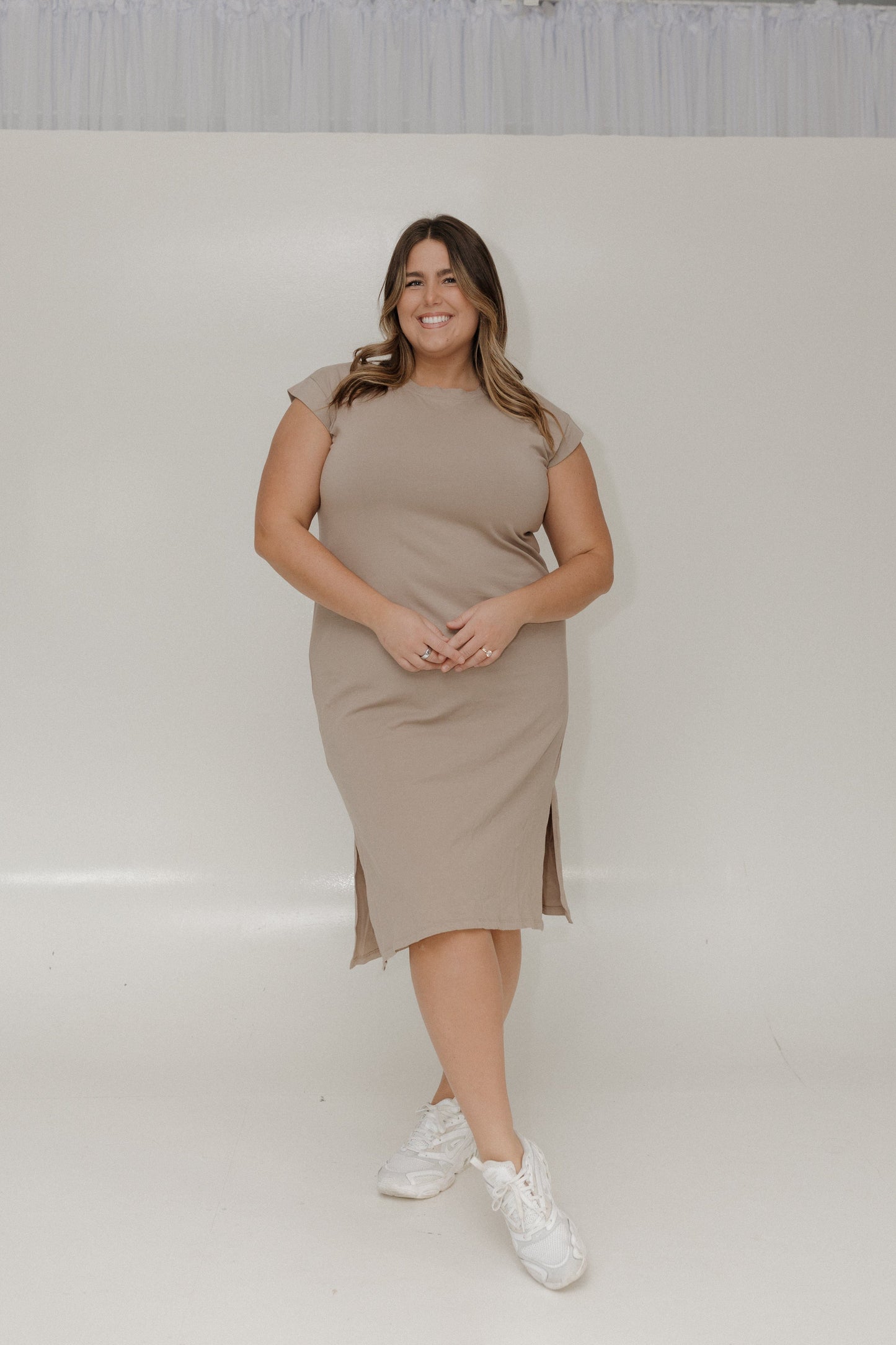 Woman wearing a beige dress standing against a plain background