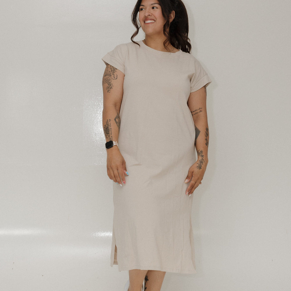 Woman wearing a beige dress standing against a white background