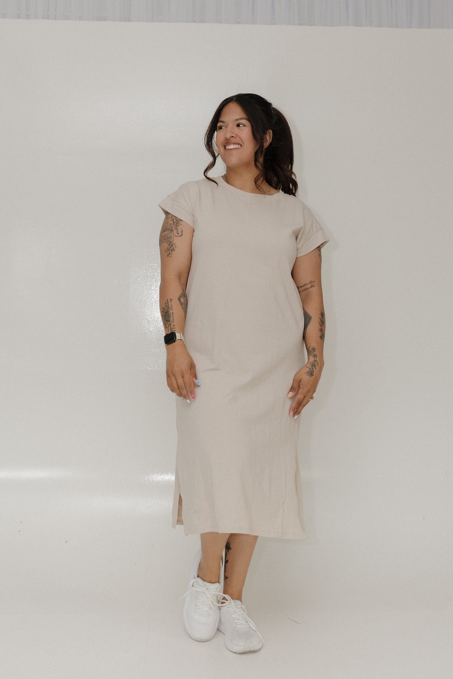 Woman wearing a beige dress standing against a white background