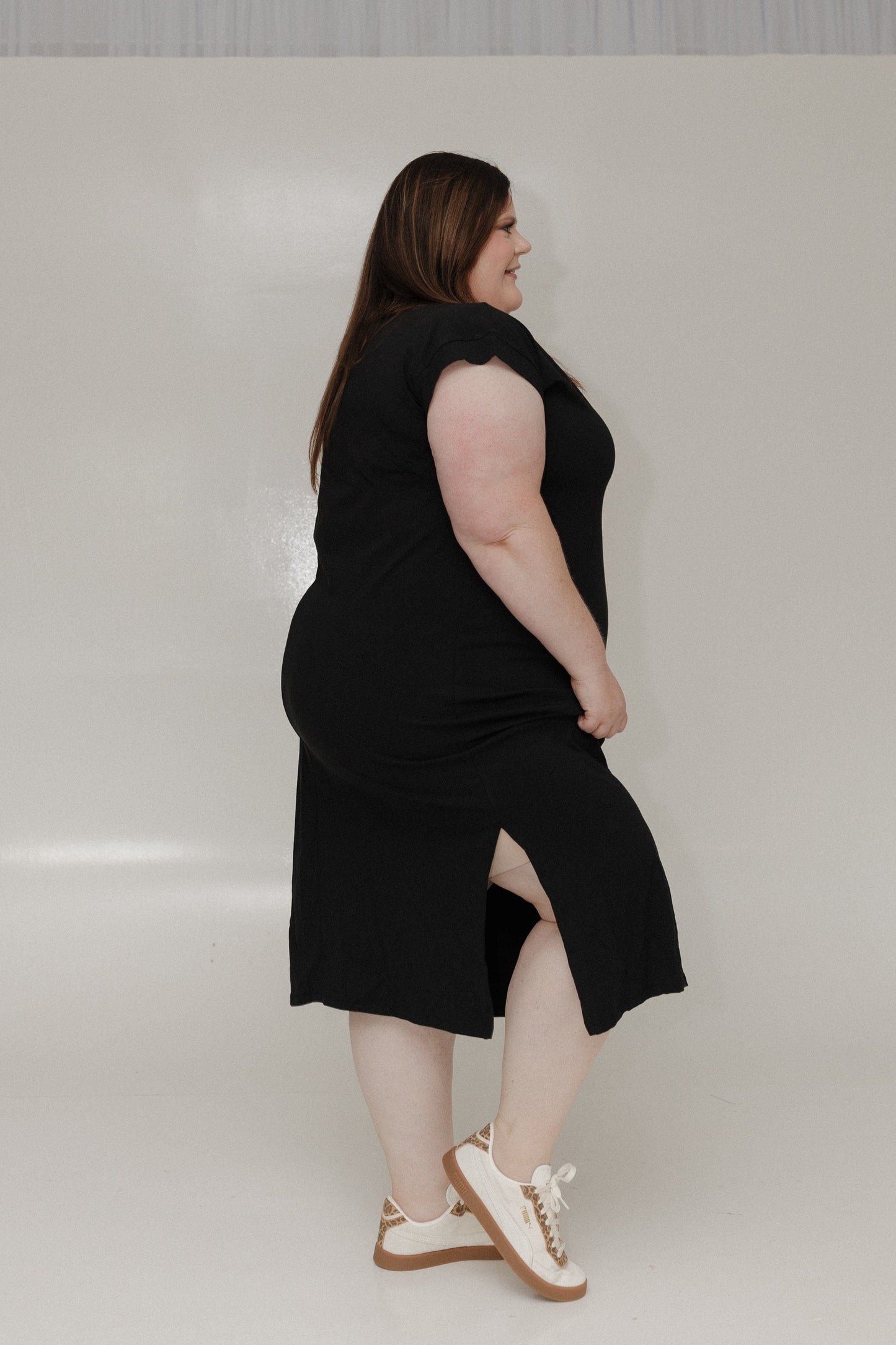 Woman wearing a black sleeveless dress against a plain background