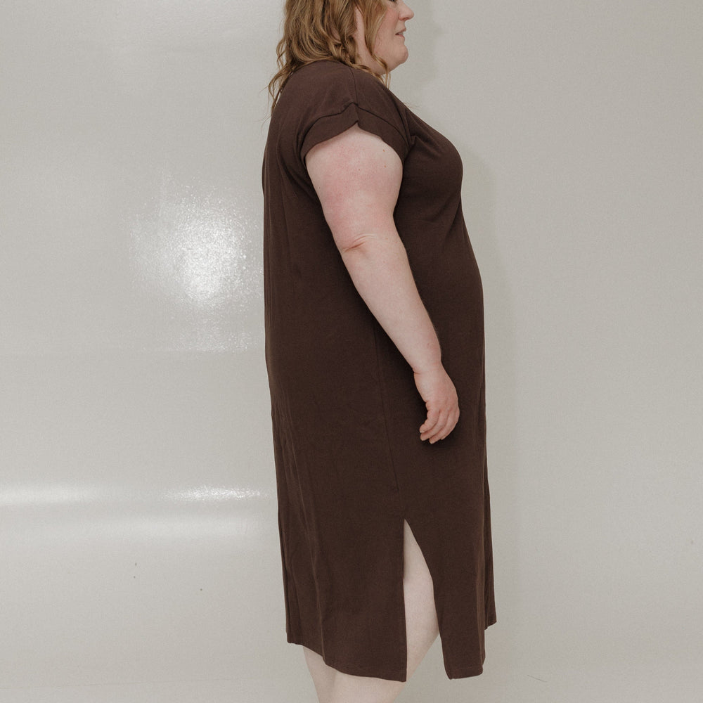 Woman wearing a brown dress with a slit on a white background