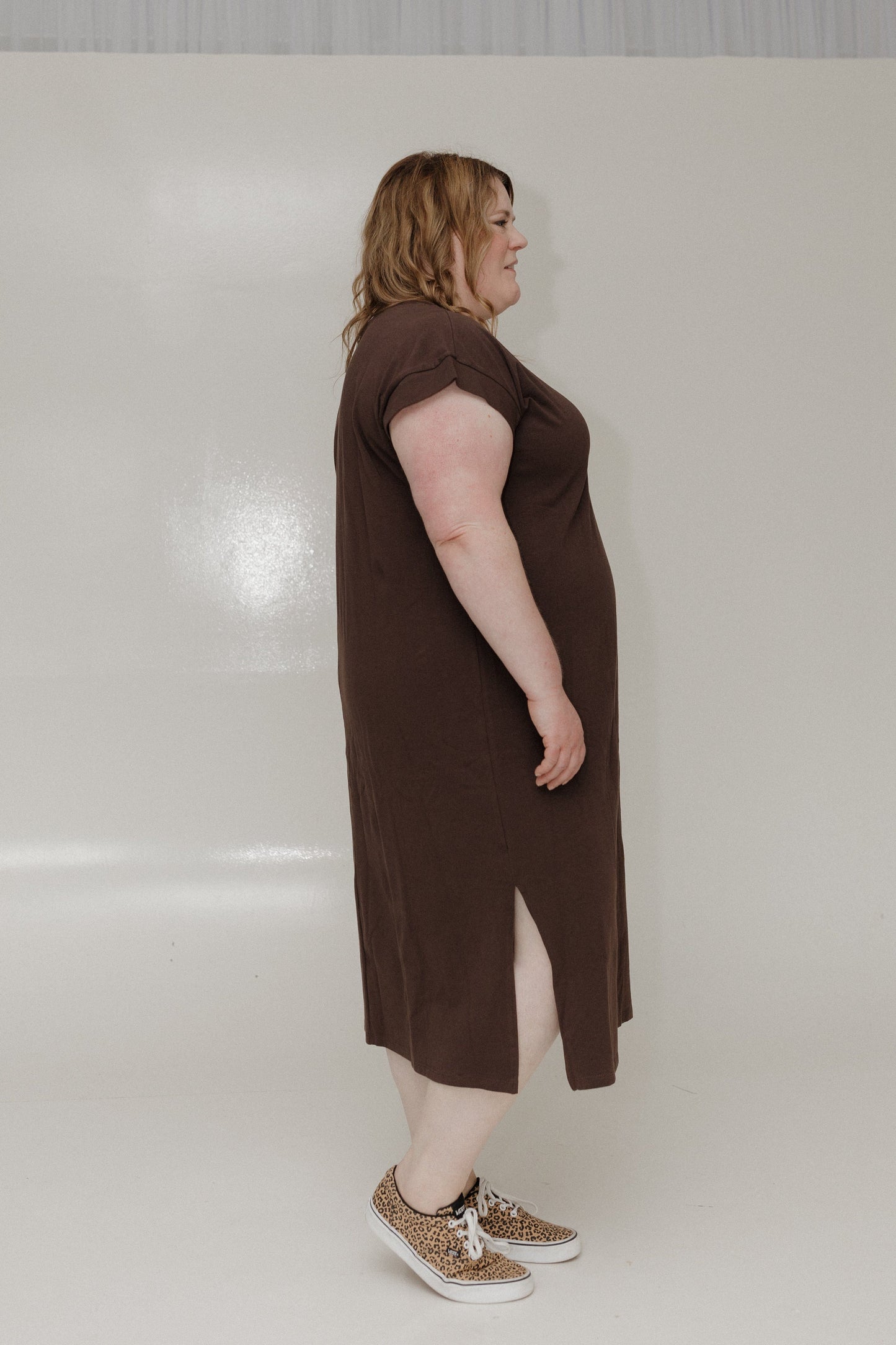 Woman wearing a brown dress with a slit on a white background