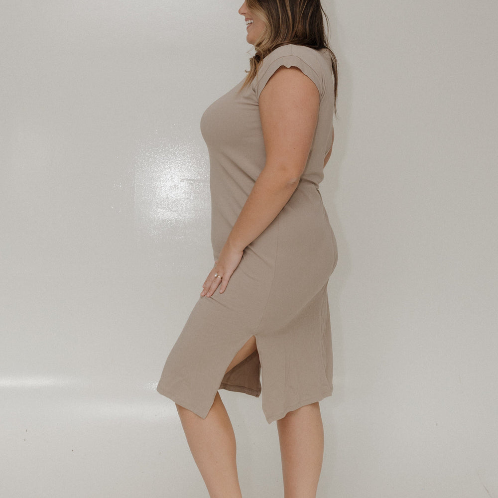 Woman wearing a beige dress standing against a plain white background