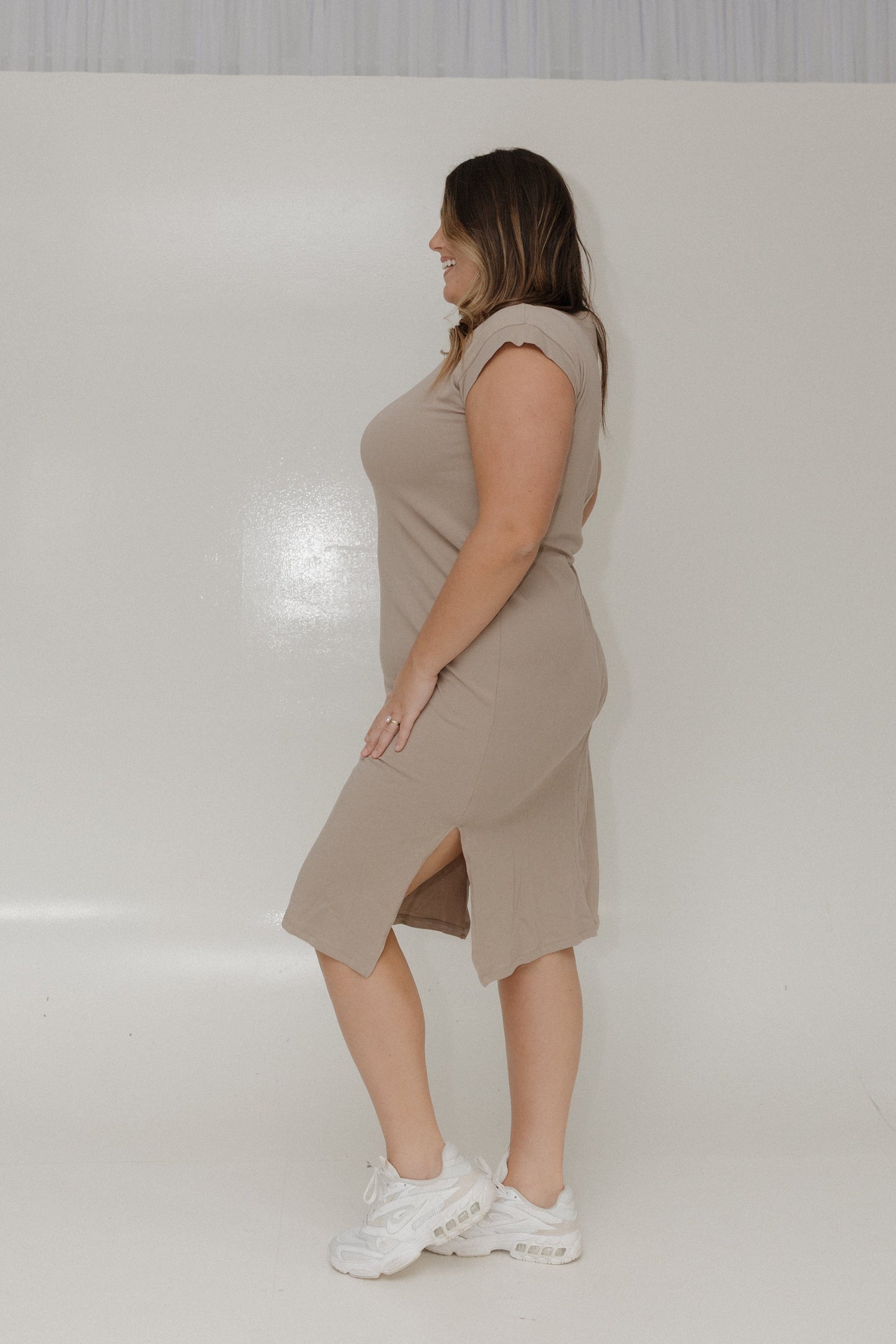 Woman wearing a beige dress standing against a plain white background