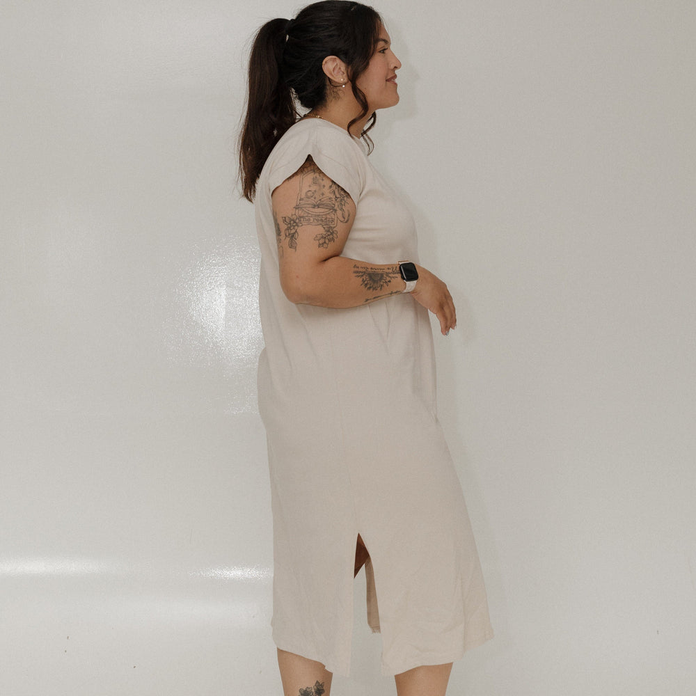 Person wearing a beige dress standing against a plain white background