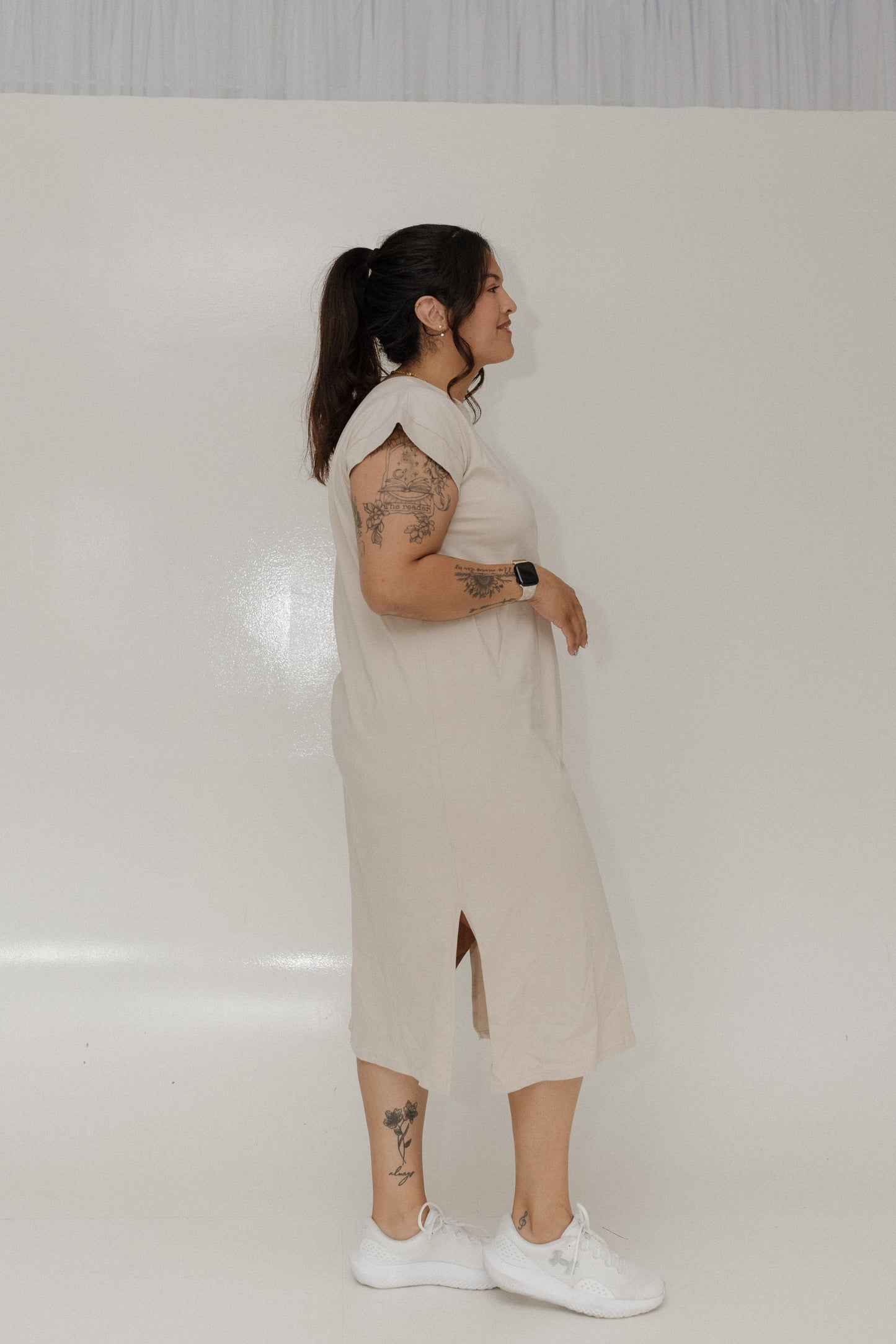 Person wearing a beige dress standing against a plain white background