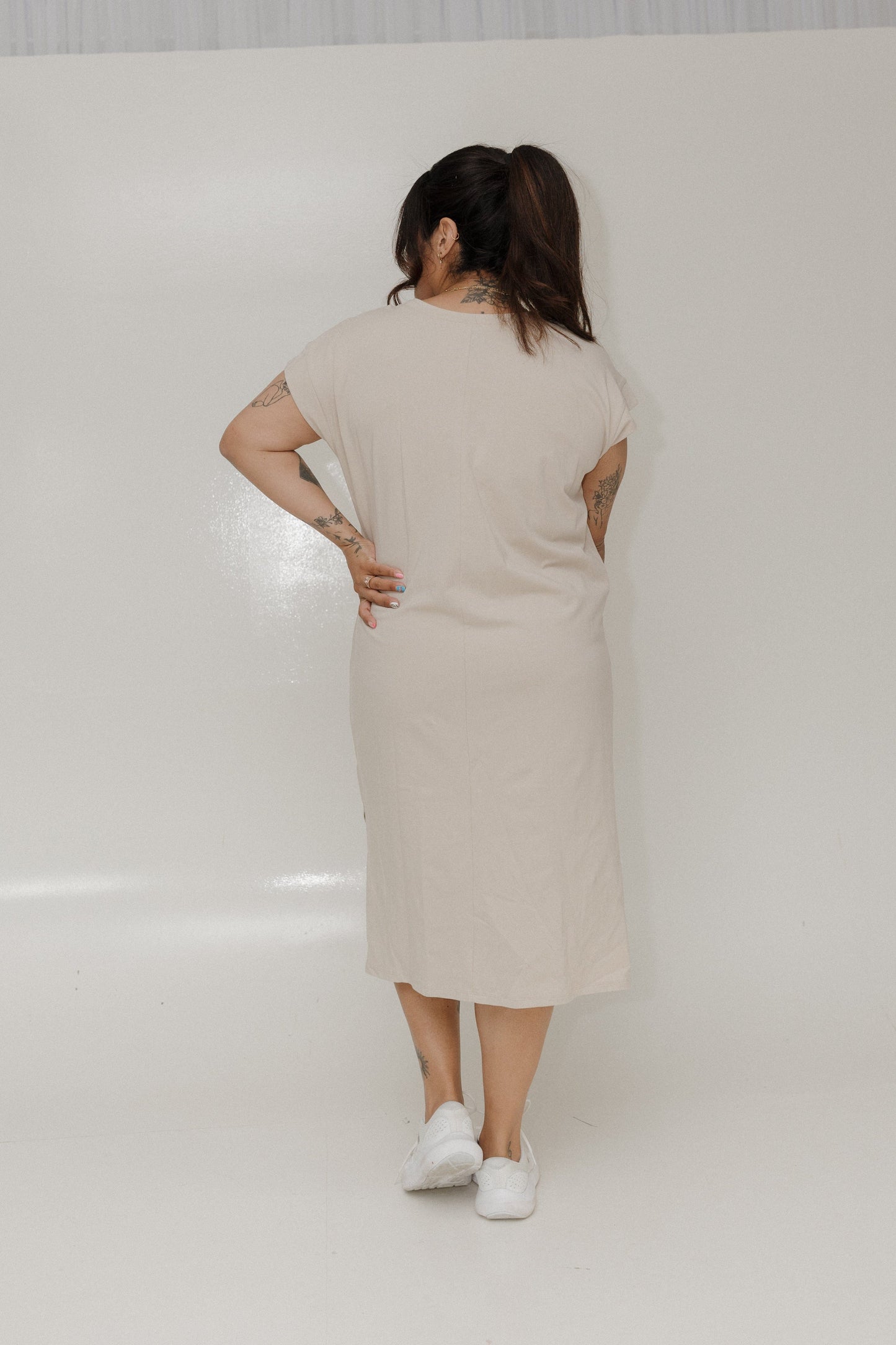 Woman wearing a beige dress standing against a white background
