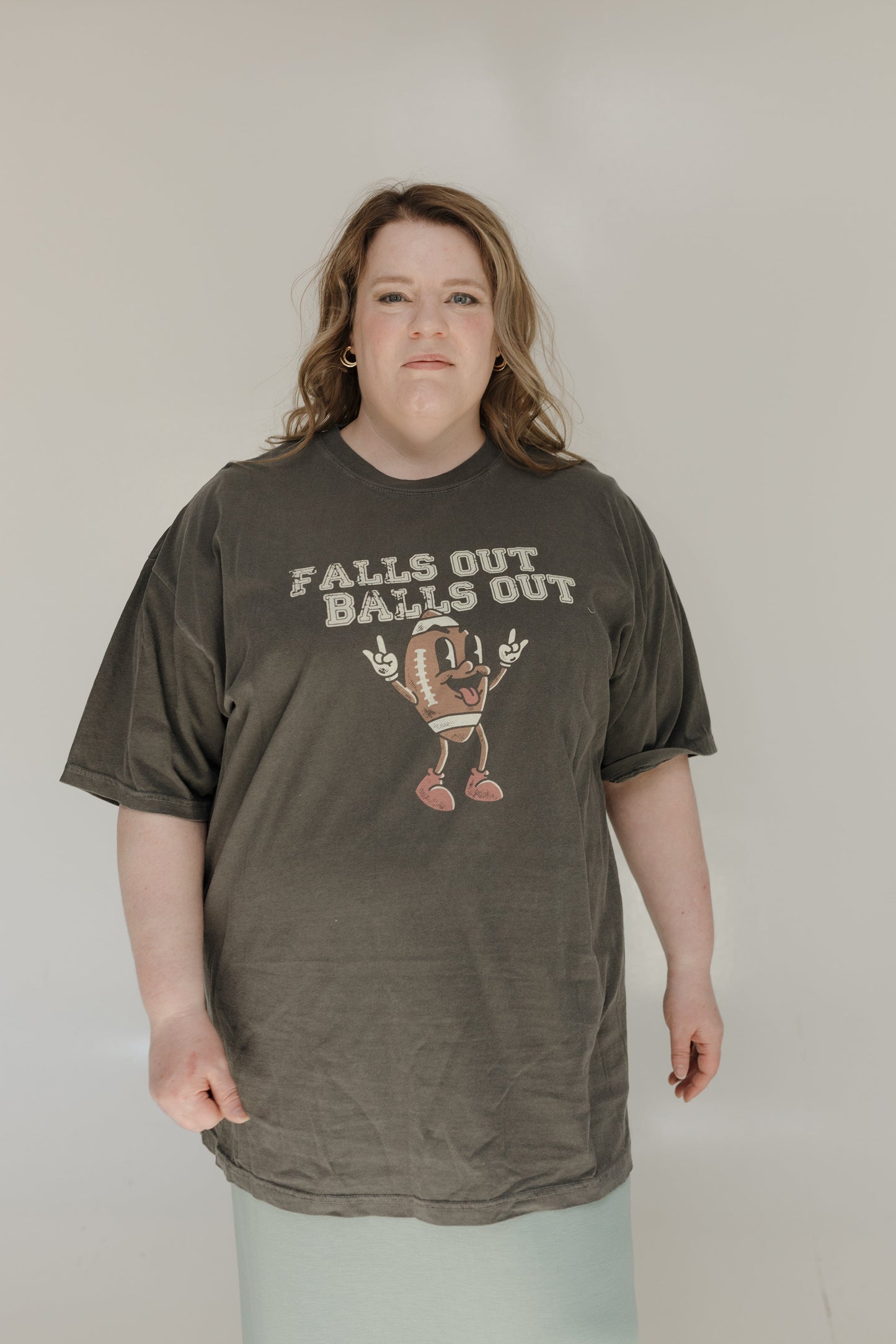 Person wearing a dark green t-shirt with graphic design and text on a plain background