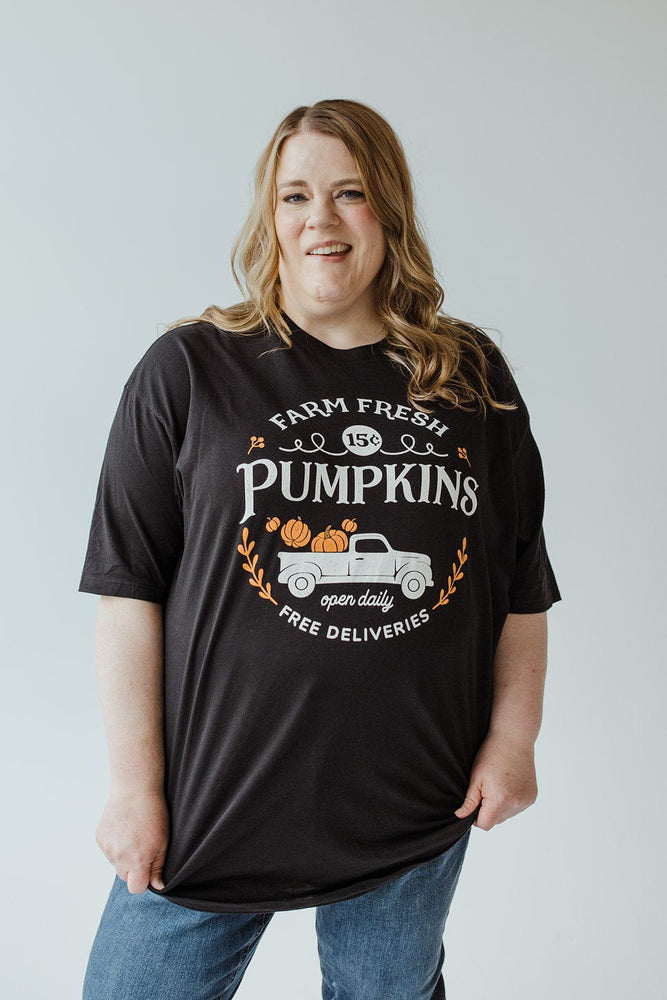 An individual wearing a Love Marlow Graphic Tee in super-soft fabric, showcasing pumpkins and a truck with the message "Farm Fresh Pumpkins, Open Daily, Free Deliveries.