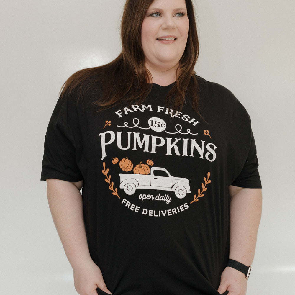 "FARM FRESH PUMPKINS" WITH TRUCK GRAPHIC TEE IN BLACK Woman wearing a black t-shirt with 'Farm Fresh Pumpkins' design against a plain background at Love Marlow