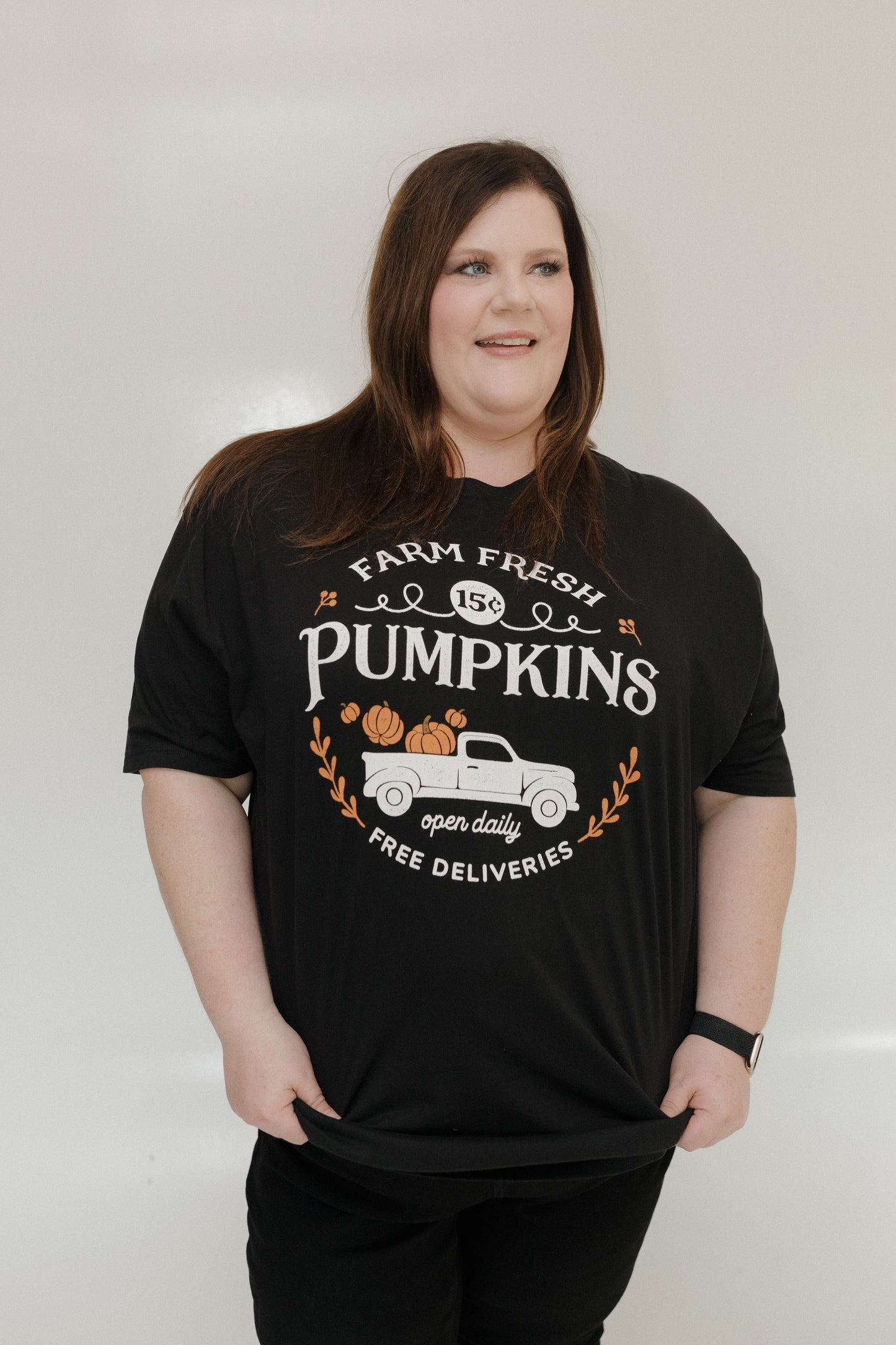 "FARM FRESH PUMPKINS" WITH TRUCK GRAPHIC TEE IN BLACK Woman wearing a black t-shirt with 'Farm Fresh Pumpkins' design against a plain background at Love Marlow