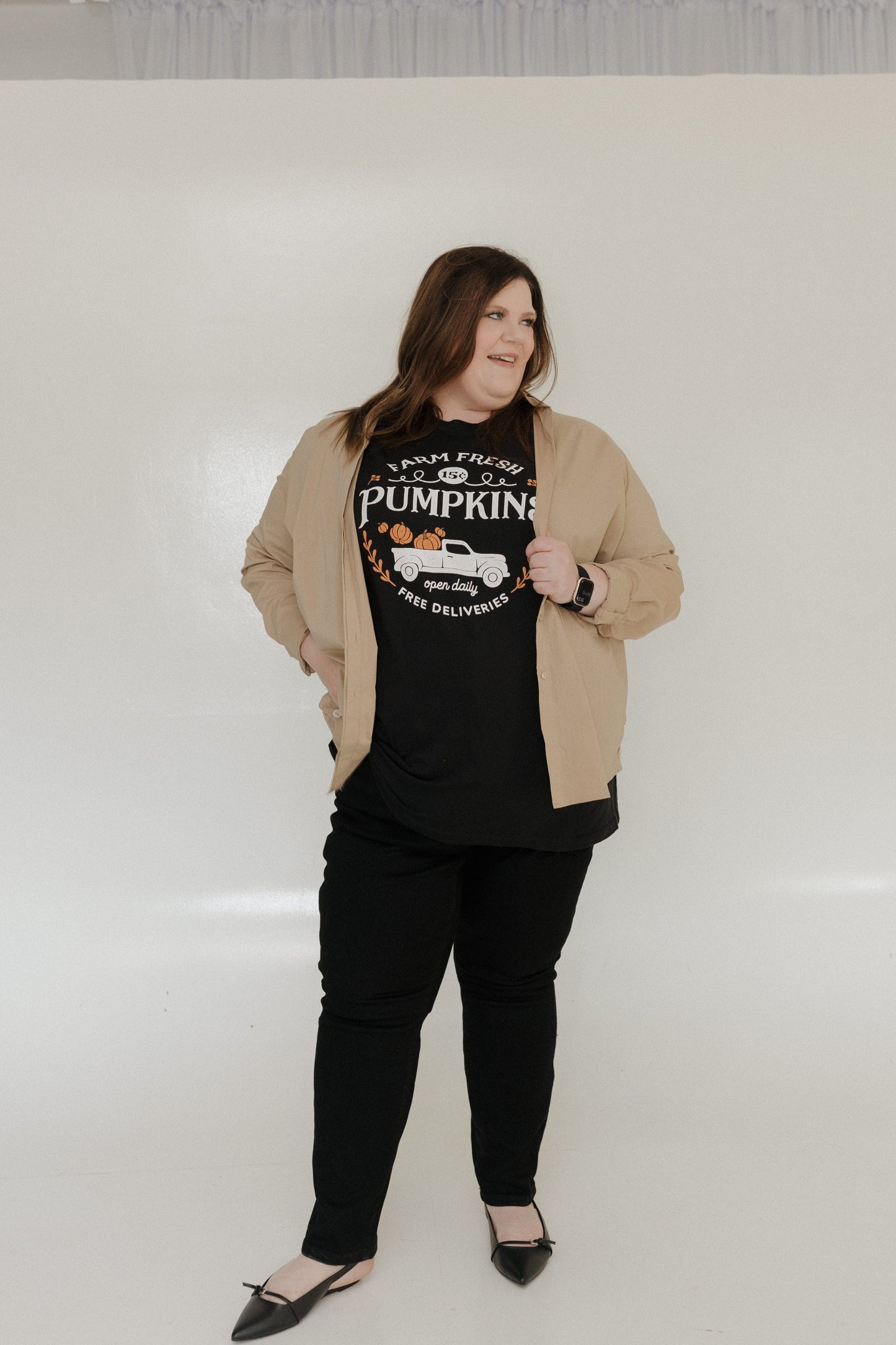 "FARM FRESH PUMPKINS" WITH TRUCK GRAPHIC TEE IN BLACK Woman wearing a black t-shirt with 'Farm Fresh Pumpkins' design against a plain background at Love Marlow