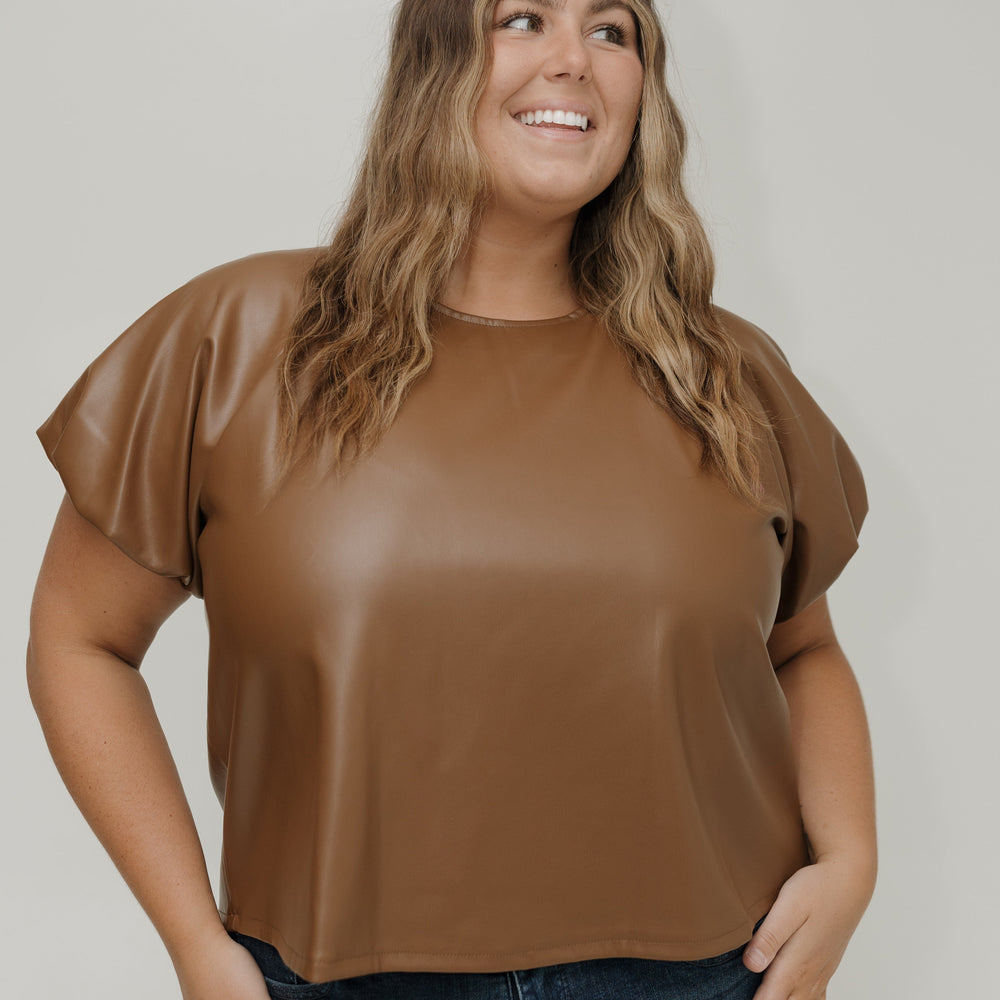 Woman wearing a brown top and blue jeans against a white background