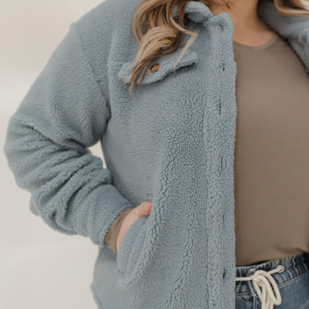 Person wearing a light blue fleece jacket with a neutral background