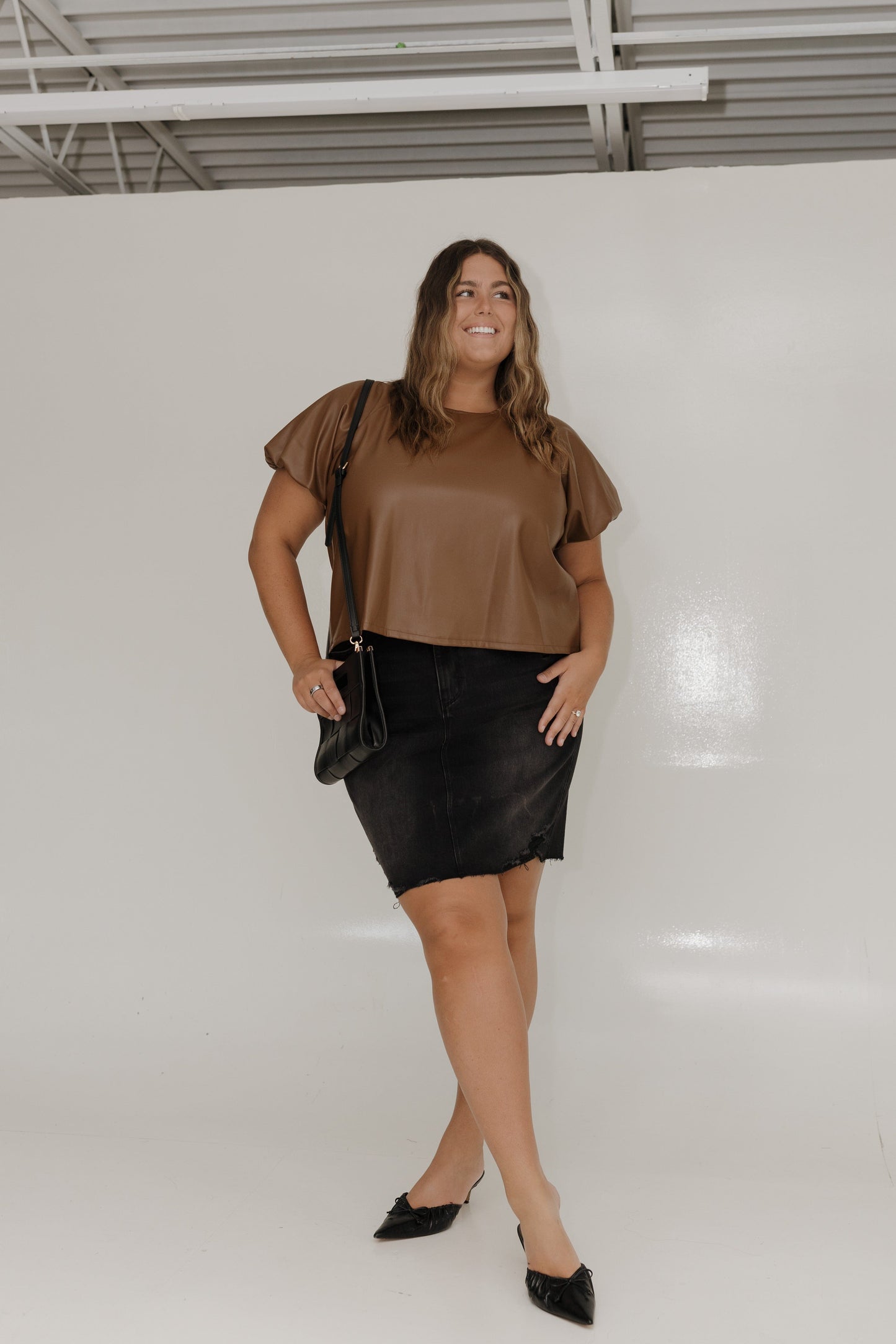 Woman wearing a brown top and black skirt against a white background