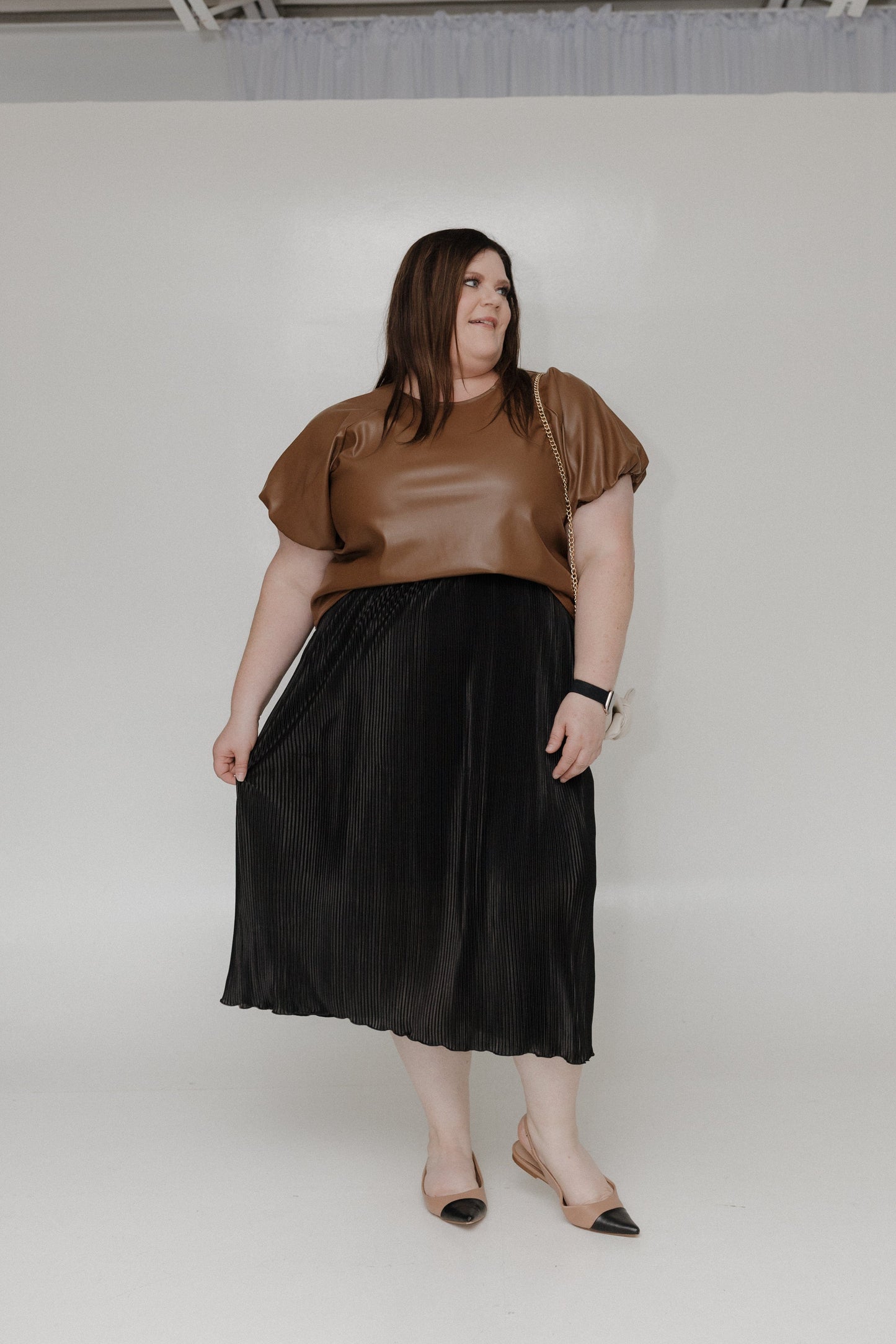 Woman wearing a brown top and black skirt against a white background