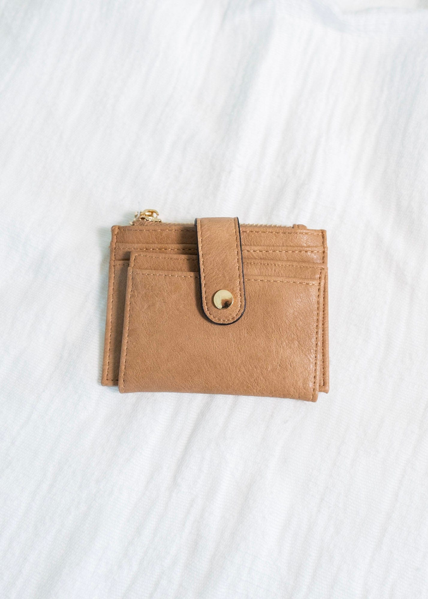 This stylish FAUX LEATHER WALLET IN MOCHA is perfect for carrying your cards and change while on the go. It features a fold-out design with a snap closure, card and ID slots, and a convenient zip change pocket. Enjoy quick access and organized storage with this classic wallet.