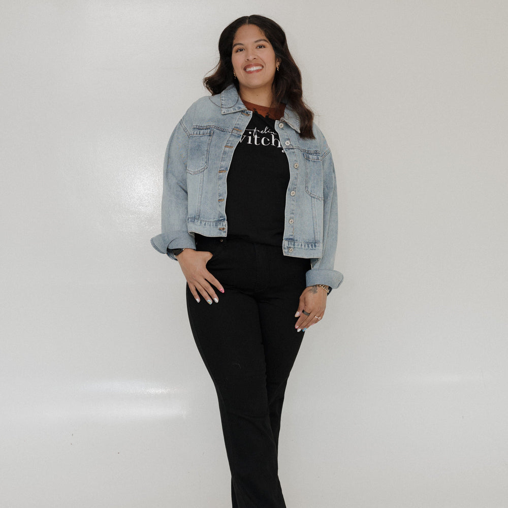 "FEELIN' WITCHY" GRAPHIC TEE
Woman wearing a black t-shirt with 'feel witchy' text on a plain background. Love Marlow Tee "Feelin Witchy" in a denim jacket