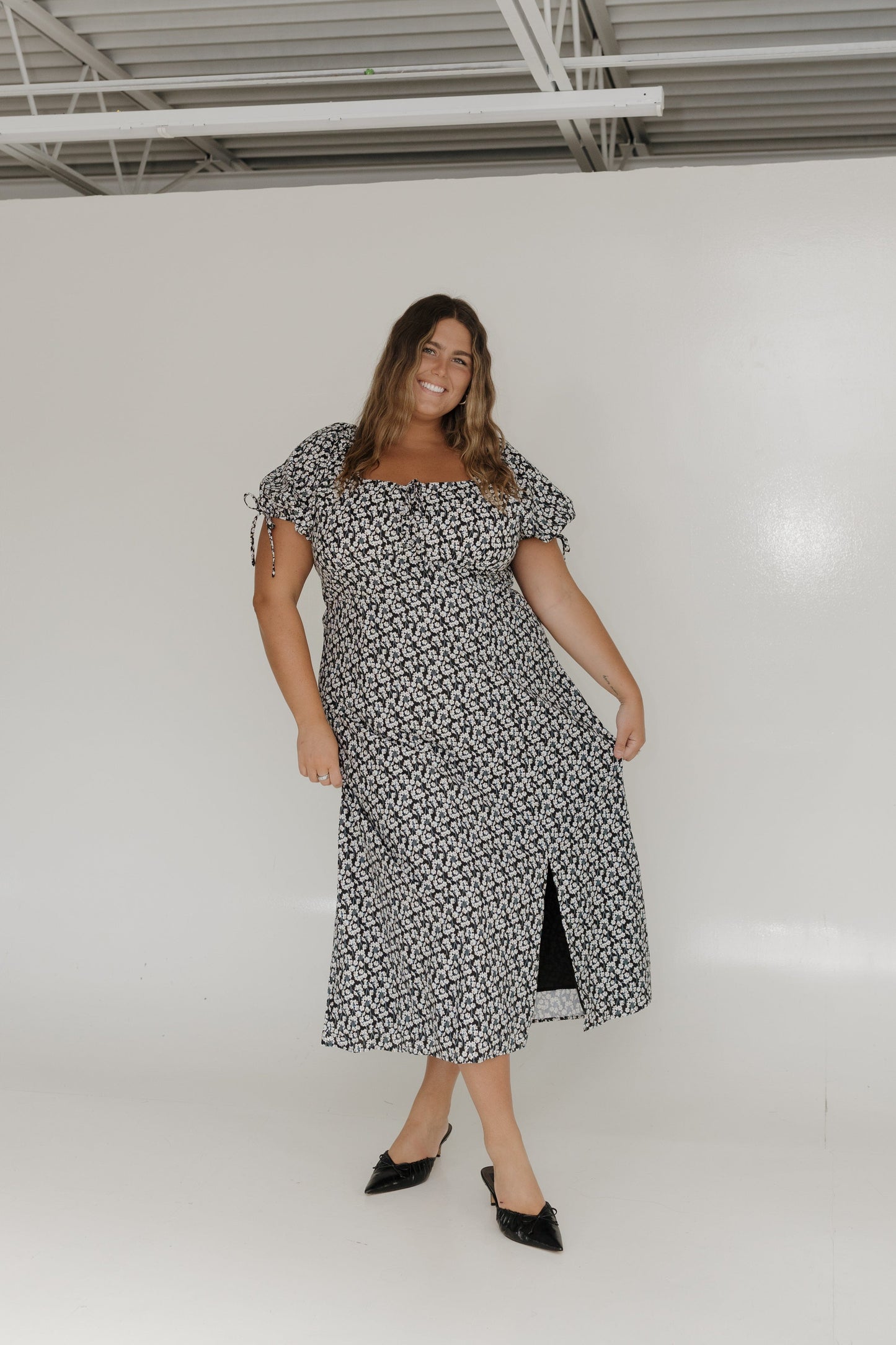 Woman wearing a black and white floral dress against a plain background