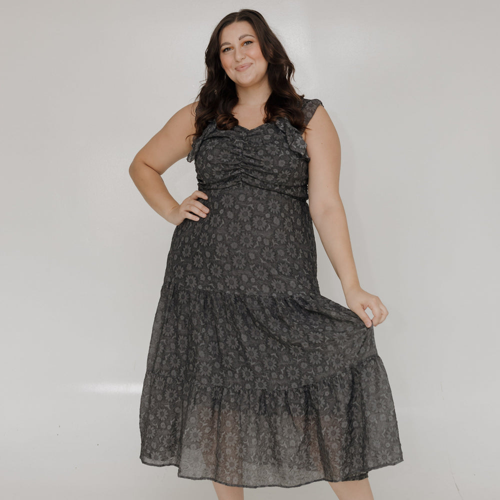 Woman wearing a black patterned dress against a white background